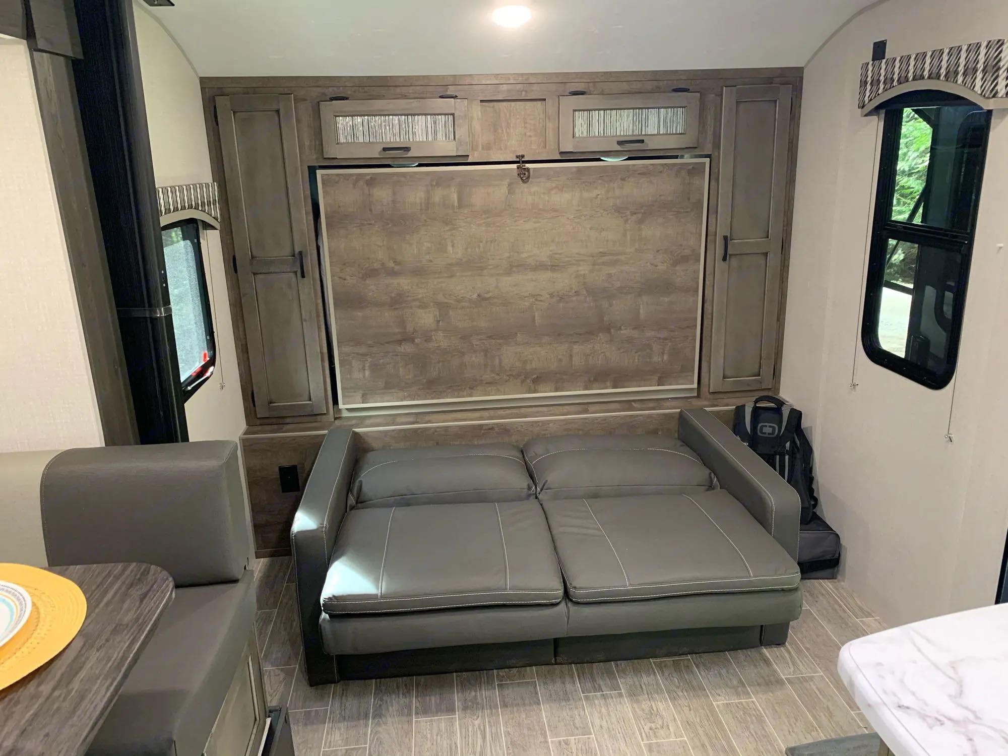 Inside an RV rental: a convertible sofa, wall-mounted murphy bed, and dinette maximizing compact living space.. Sonic Sonic Trailer 2025