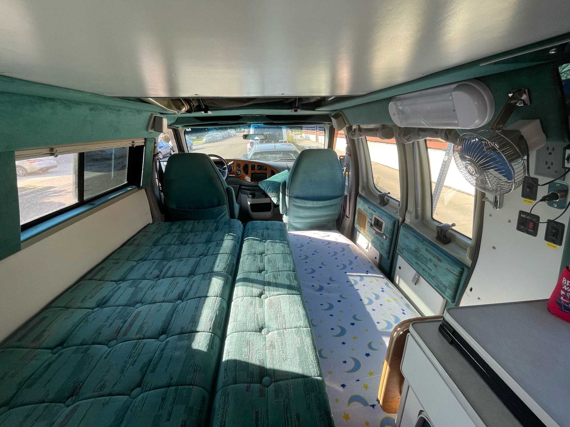 RV rental interior: A spacious camper van with teal upholstered beds and front cabin view.. Sportsmobile E350 1997