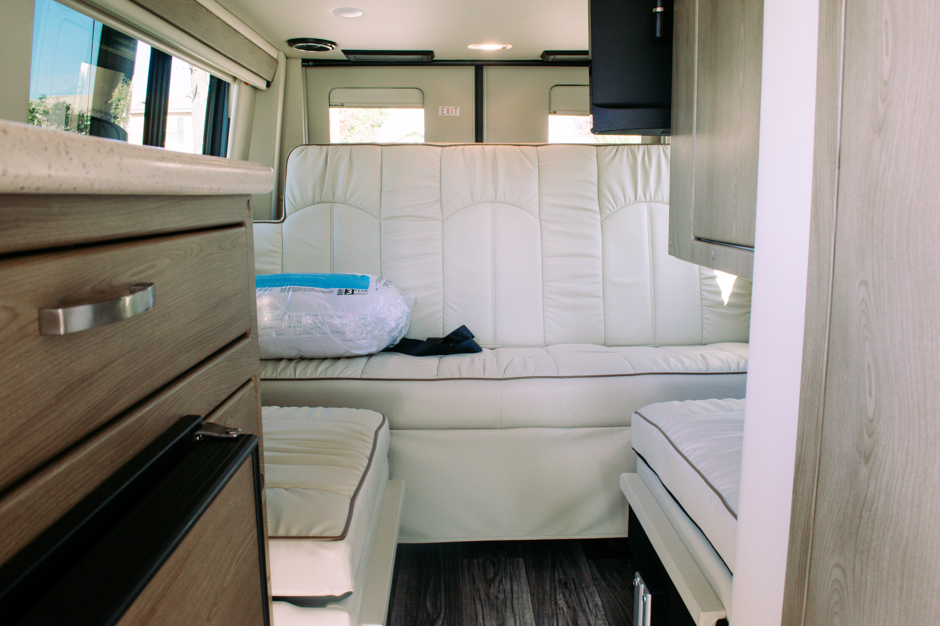 Looking into an RV rental's modern interior. Features cream sofa-bed, wood cabinets, and TV, offering a cozy, functional living space.. Midwest Automotive Design Mercedes Benz passage 2022