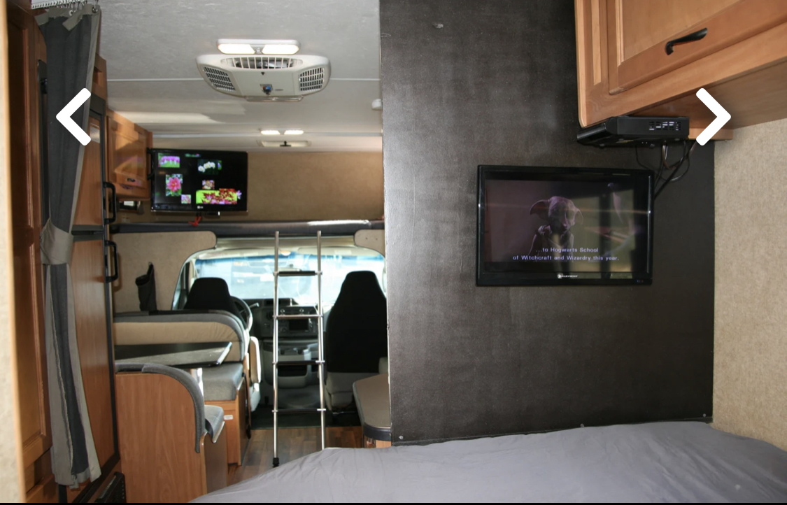 Explore a comfortable RV rental interior showing a dinette, bunk, and dual TVs for entertainment.. Thor Majestic 2017