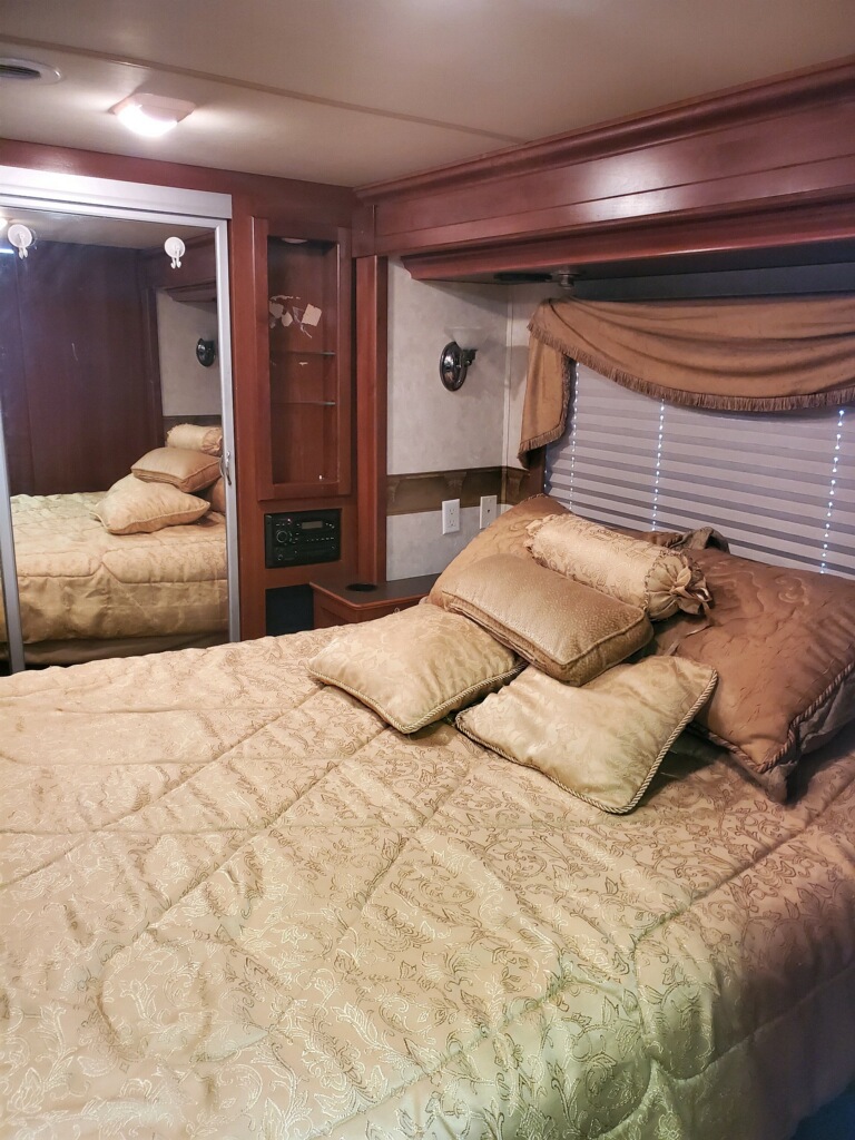 Cozy RV rental bedroom with comfortable bed, mirrored closet, and wood accents.. Fleetwood Discovery 2004