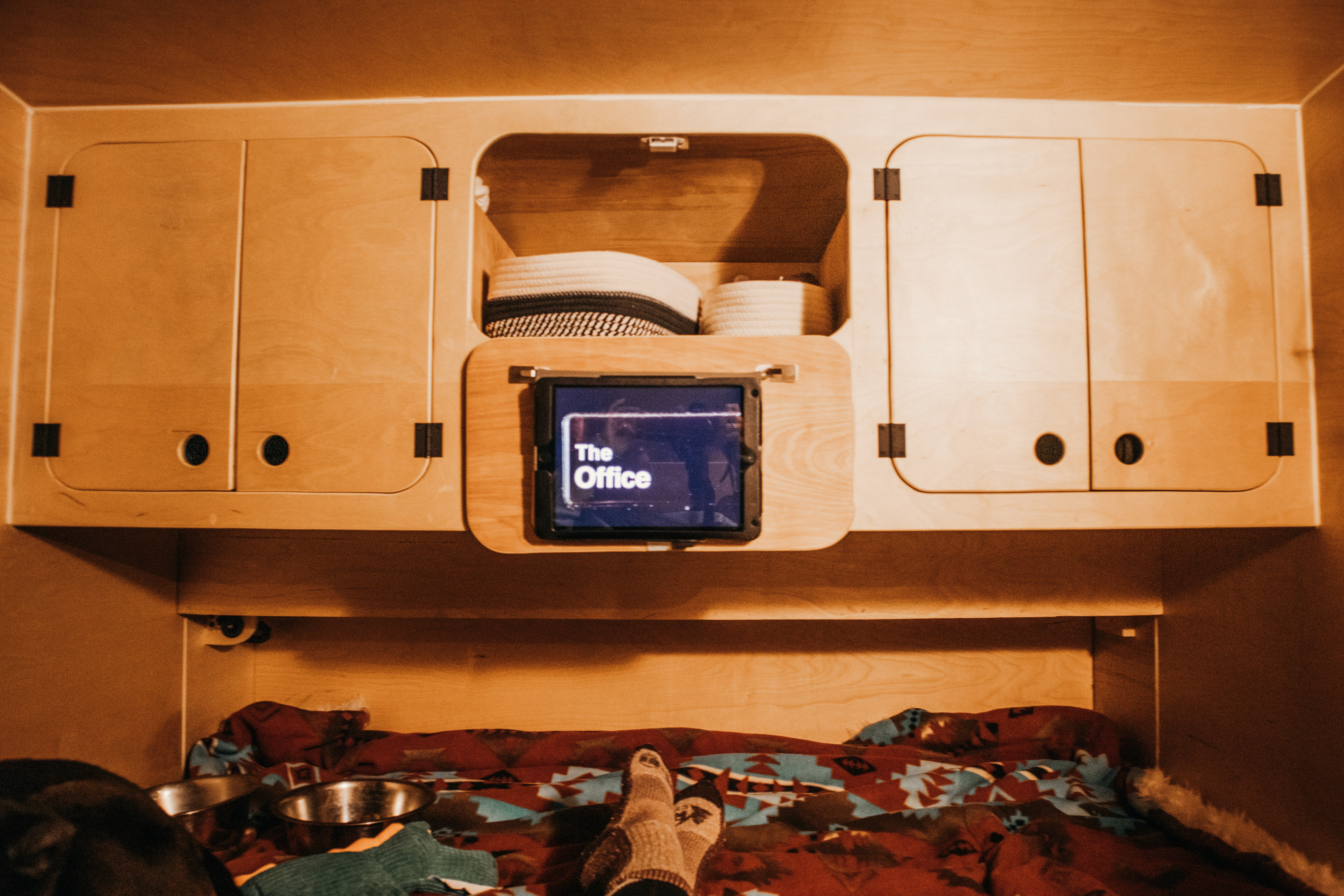 Relax in a cozy RV rental: watching "The Office" on a tablet in a wooden interior with storage and pet bowls.. Wander Tears Vaga 2020