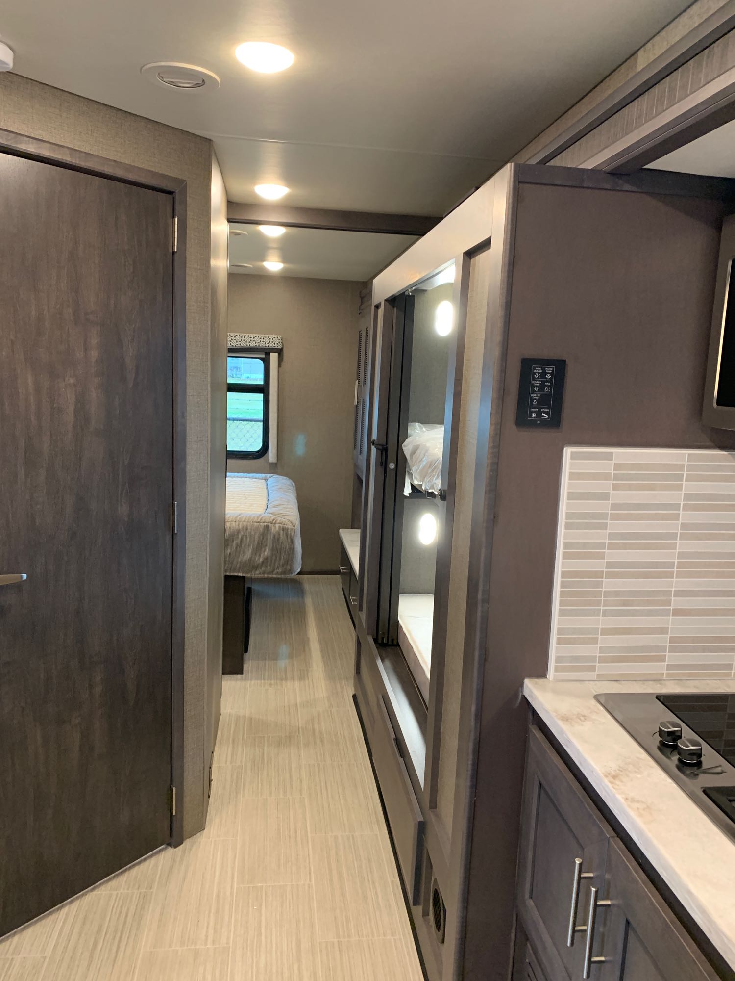 Step inside this rv rental: hallway to a bedroom, kitchen with stove, and lit bunk beds offer compact living.. Thor Magnitude 2021