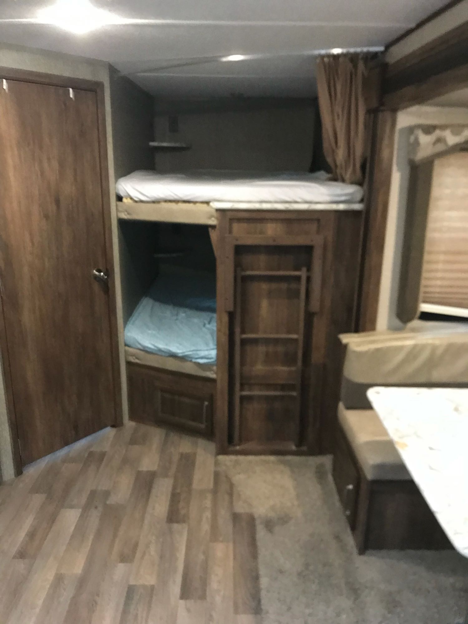 Cozy bunkhouse style RV rental interior featuring comfortable beds and a dinette area, ideal for family travel.. Keystone Cougar Half-Ton 2017