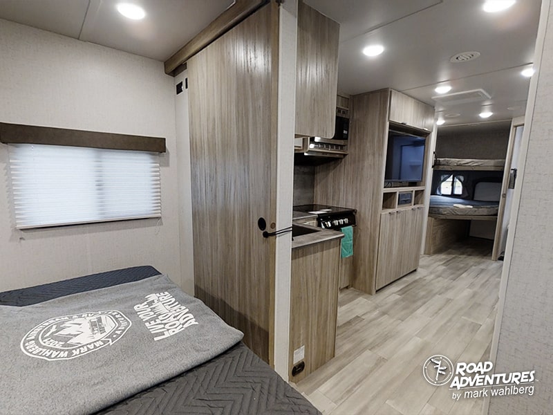 Modern rv rental interior: light wood cabinetry, bed, compact kitchen, & bunk beds for your next adventure.. Winnebago Minnie 2301BHS 2022