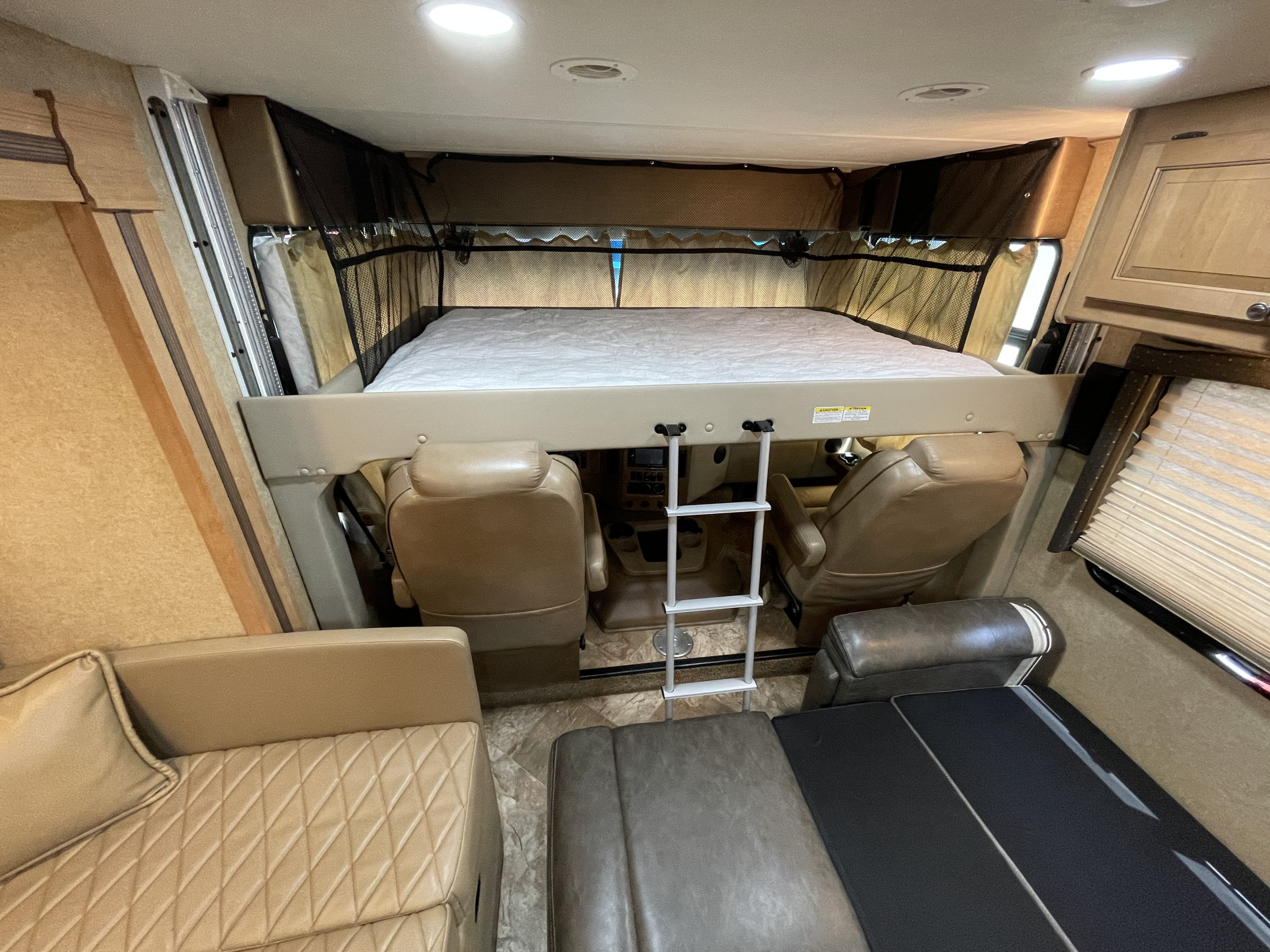 Spacious RV rental interior featuring a large cab-over bunk with ladder, cockpit seats, and comfortable living area seating.. Other Other 2016