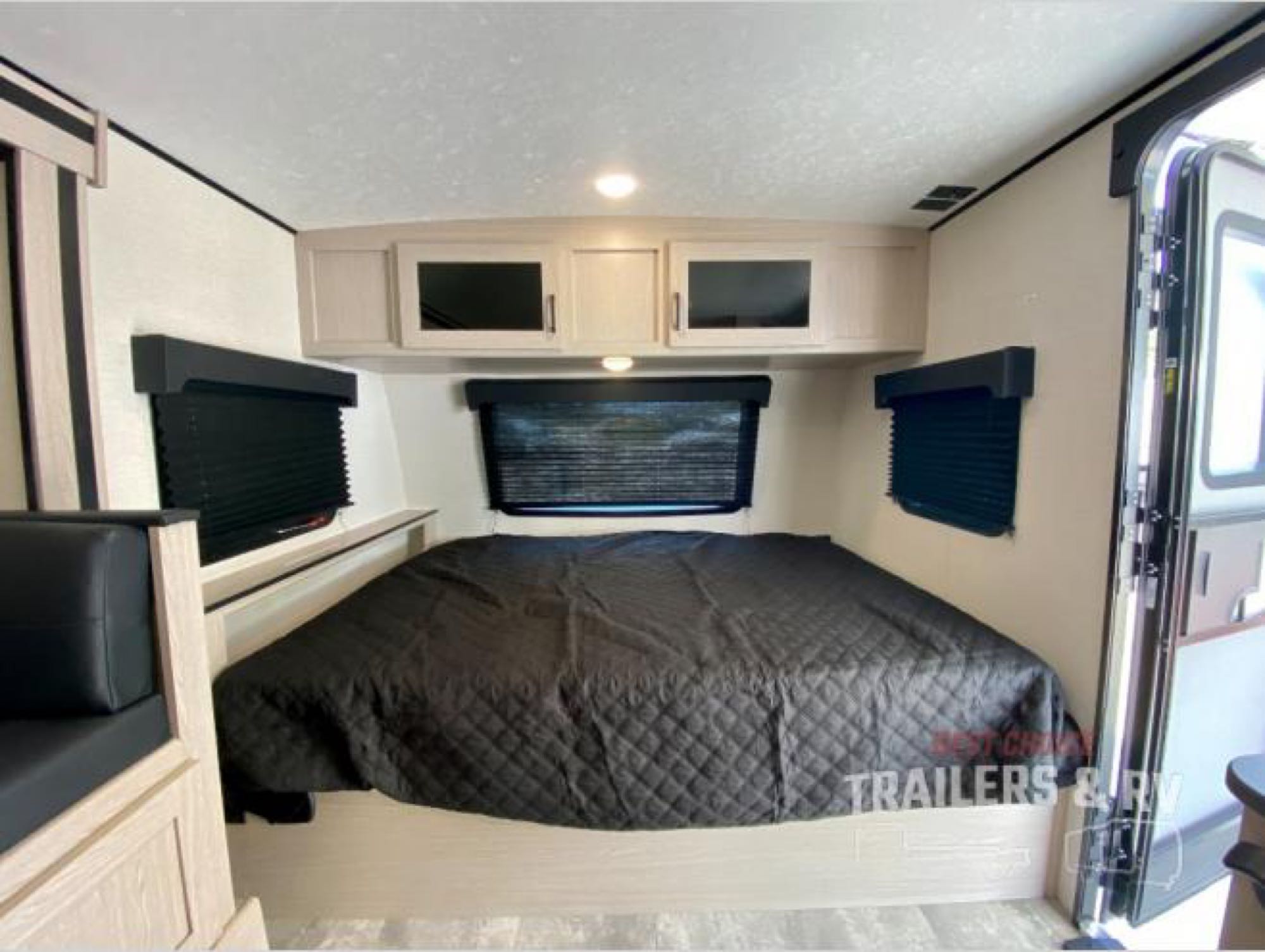 Cozy RV rental interior with a spacious bed, overhead storage, and natural light from multiple windows. Perfect for travelers.. Coachmen Apex 2022