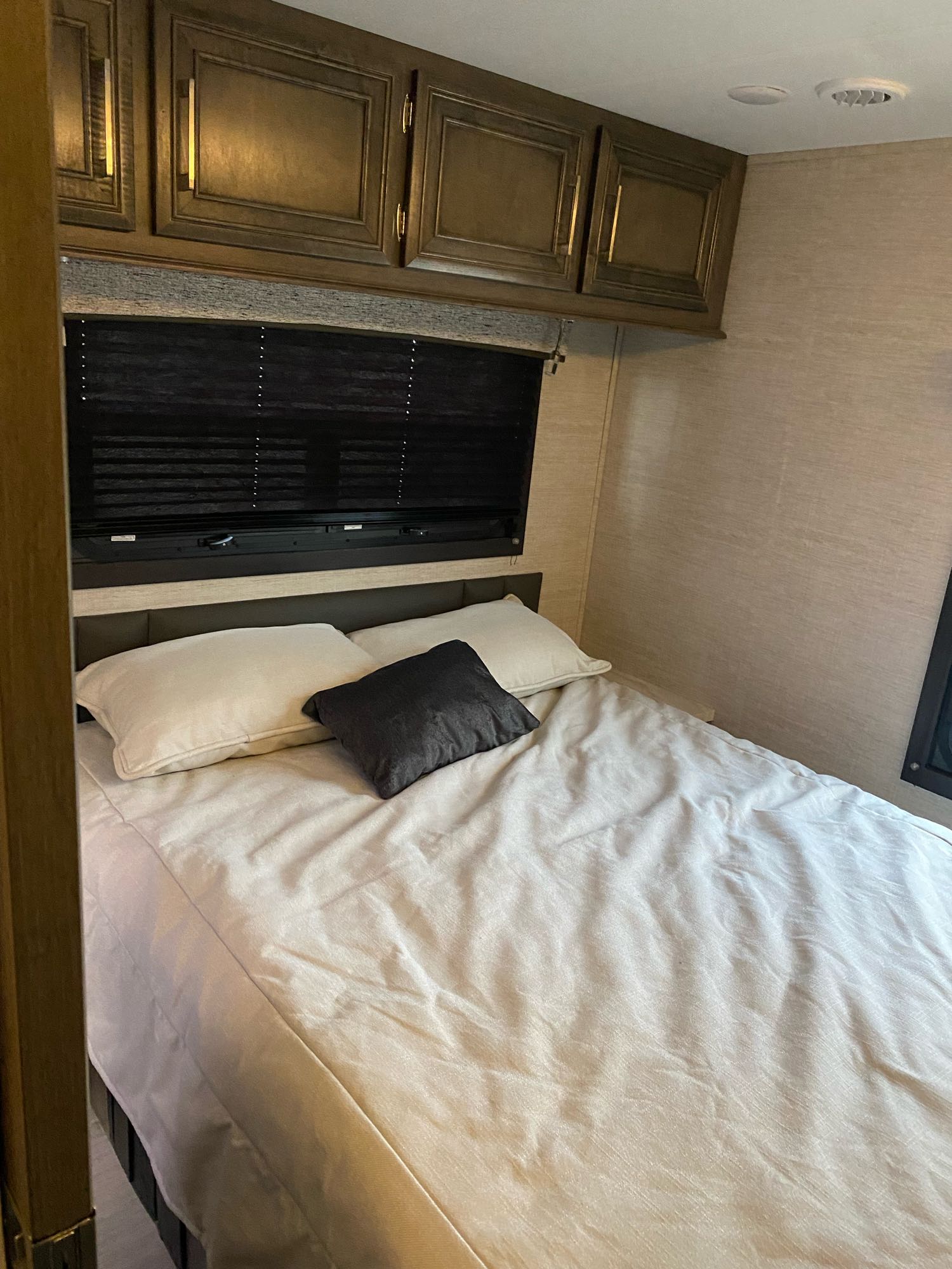Cozy RV rental bedroom with a comfortable bed, overhead cabinets, and window blinds, providing a restful space.. Entegra Coach Odyssey 2021