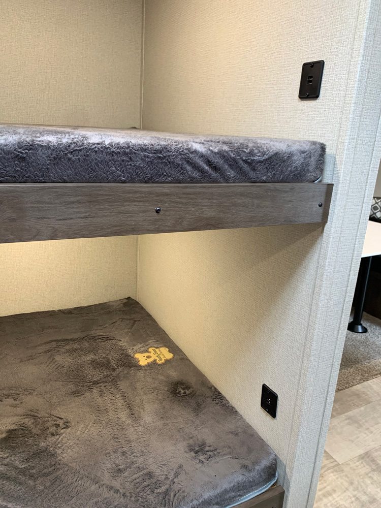 Cozy bunk beds in an RV rental, featuring soft gray mattresses, under-bunk lighting, and power outlets.. Prime Time Avenger 2021