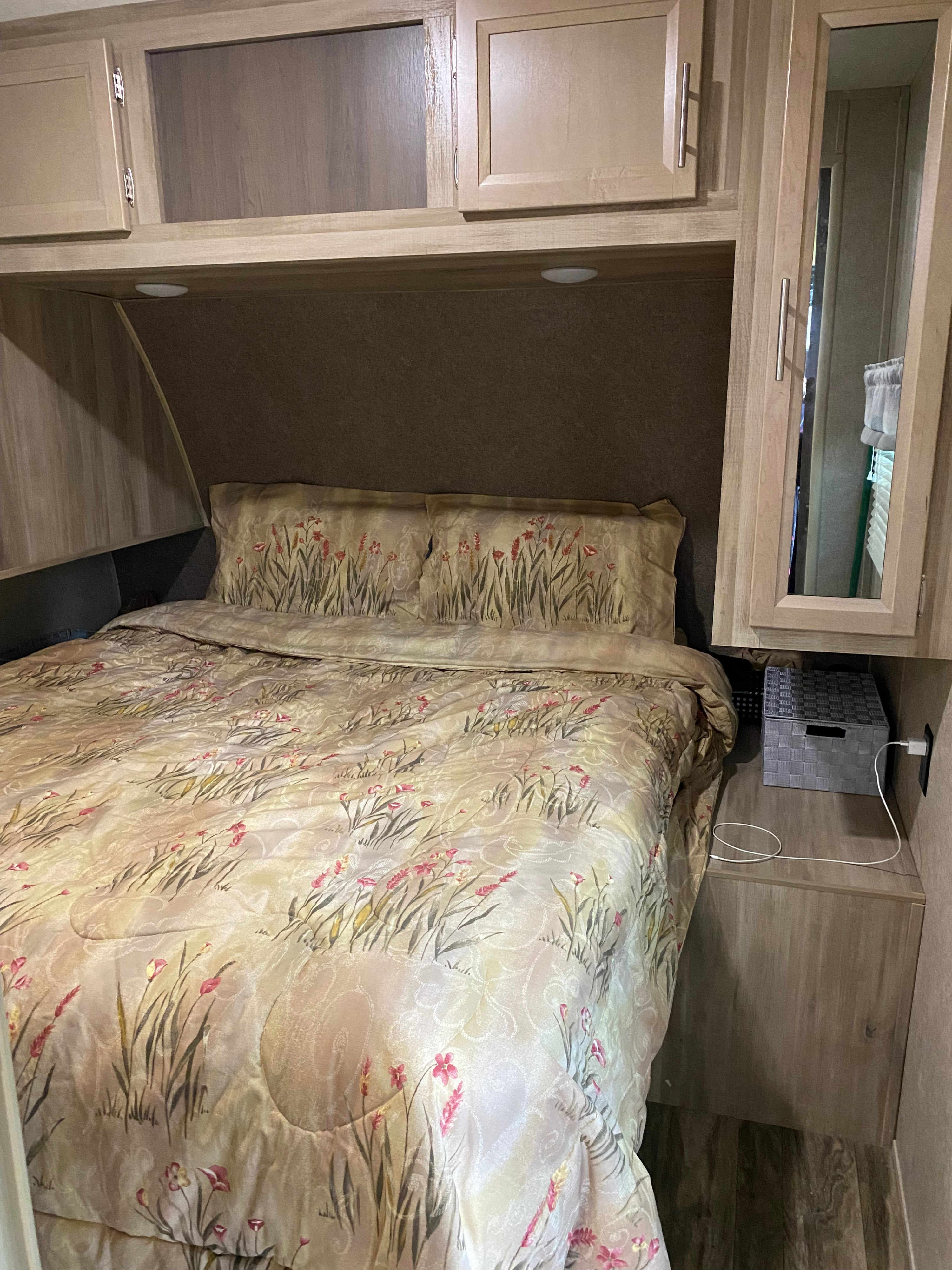 Cozy RV rental bedroom with floral bedding, overhead cabinets, and convenient charging station.. Forest River Coachmen Catalina Destination 2019
