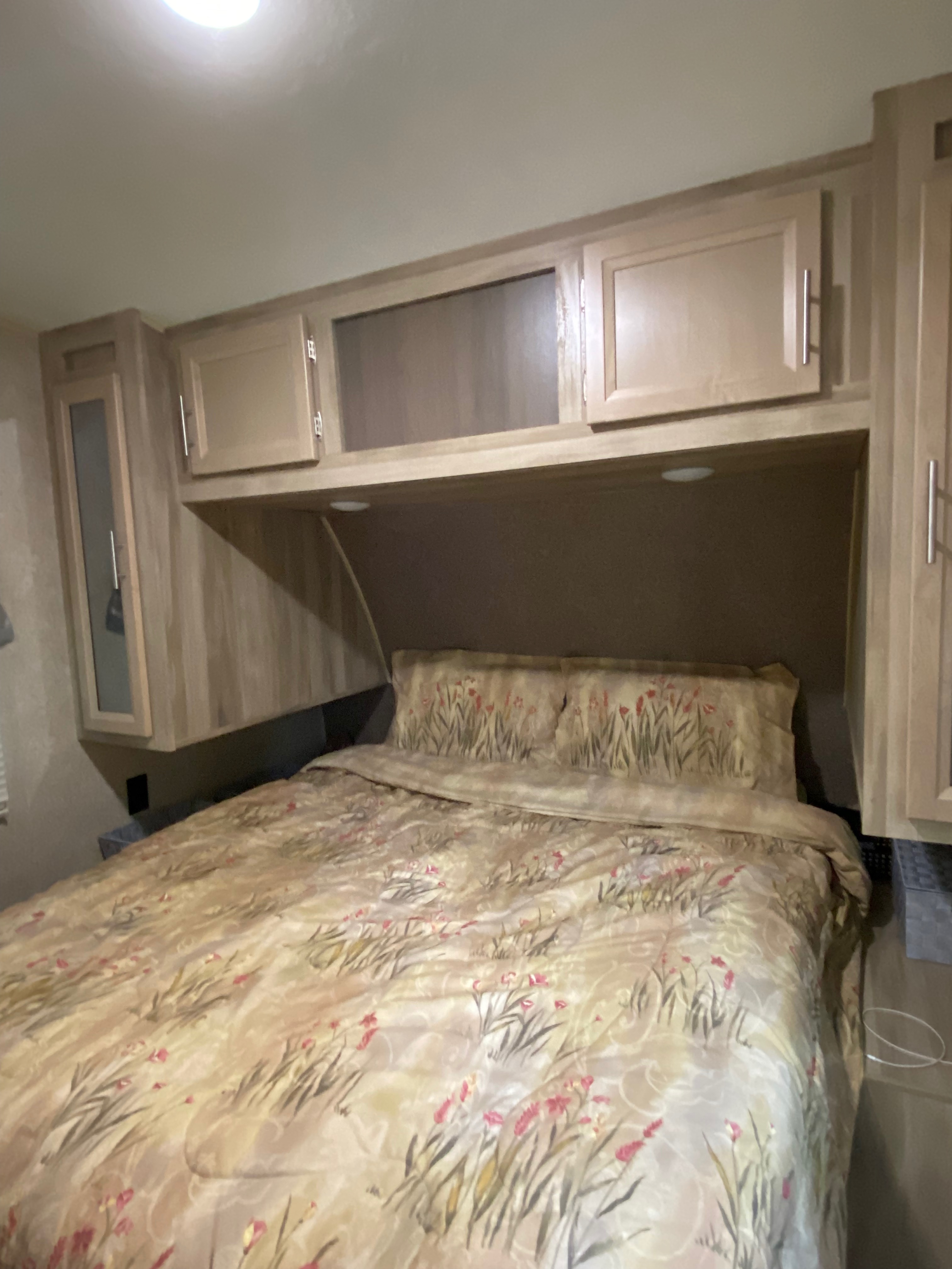 RV rental: Cozy bedroom with bed, floral bedding, and light wood overhead cabinets, some with glass inserts.. Forest River Coachmen Catalina Destination 2019