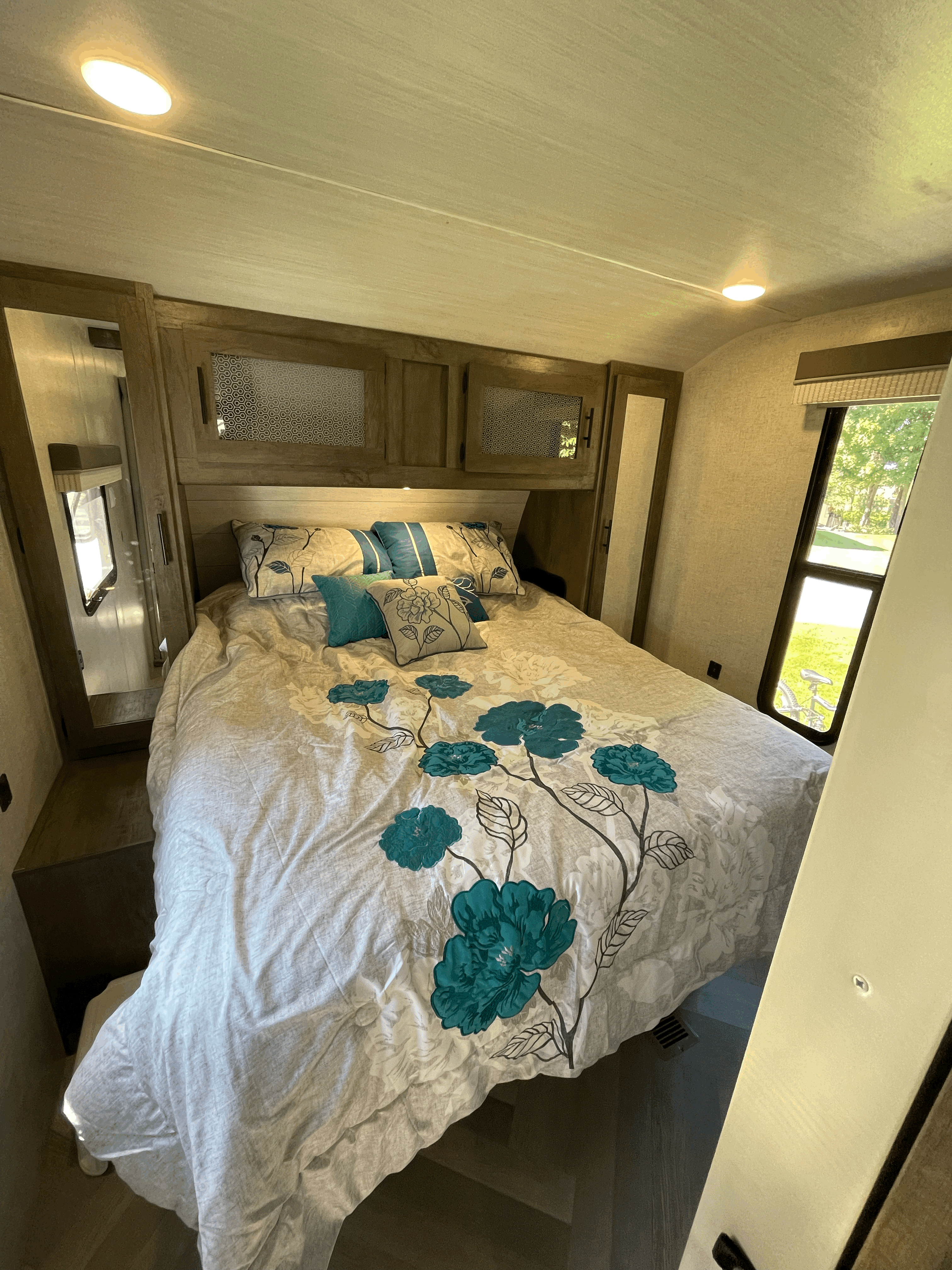 Cozy RV rental bedroom with floral bedding, overhead storage, and natural light. Enjoy comfortable travel!. Forest River Other 2021