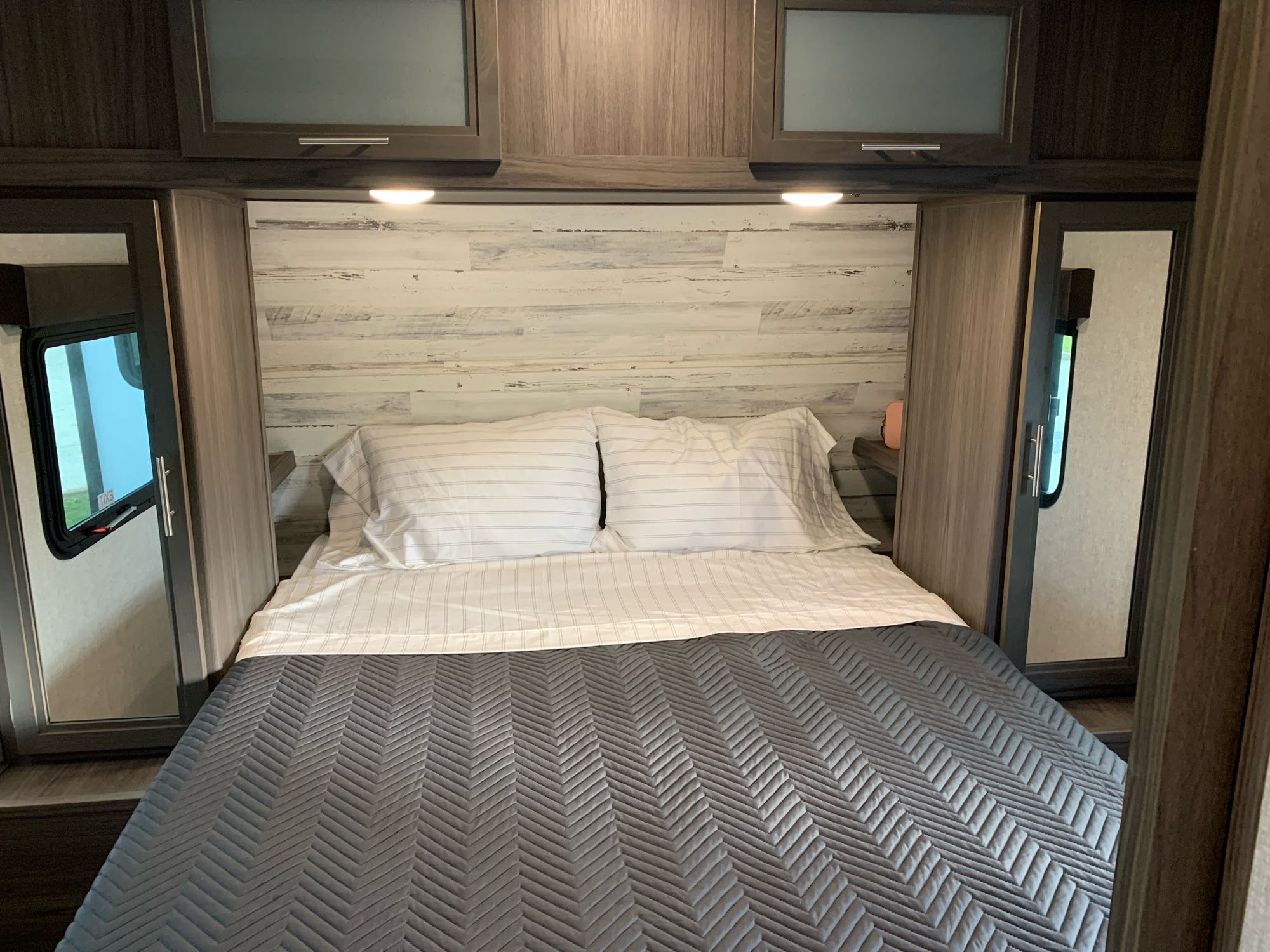 Bedroom with wardrobes, overhead storage, and cubbies behind the wardrobes with electric and USB ports. Dutchmen Kodiak Ultra Lite 2021