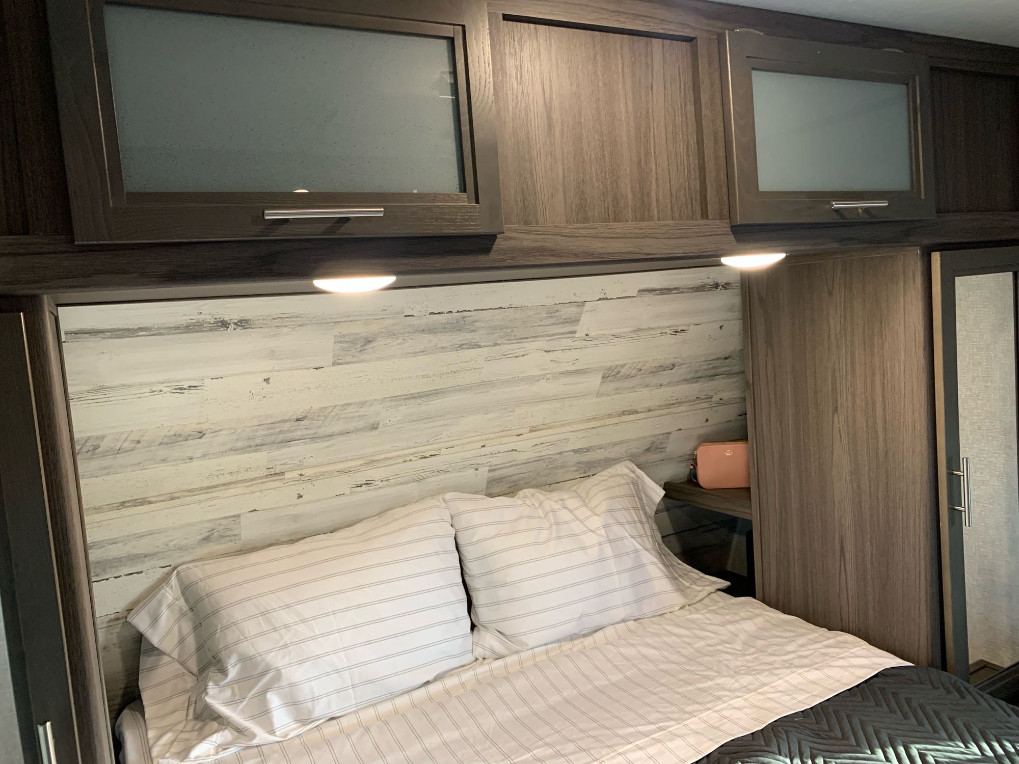 Bedroom with wardrobes, overhead storage, and cubbies behind the wardrobes with electric and USB ports. Dutchmen Kodiak Ultra Lite 2021