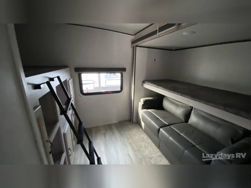 Spacious RV rental interior with bunk beds, a convertible sofa, and ladder to an upper sleeping area. Ideal for travel!. Coachmen 3379 BH 2020
