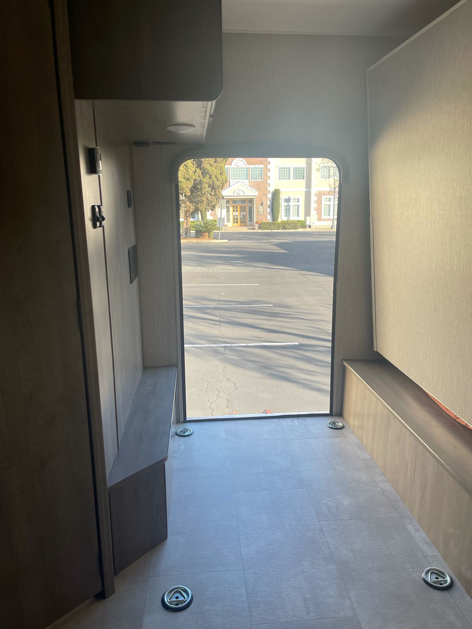 Explore this RV rental's rear cargo area with floor tie-downs & side benches, bathed in sunlight from the open ramp leading outside.. Other Other 2021