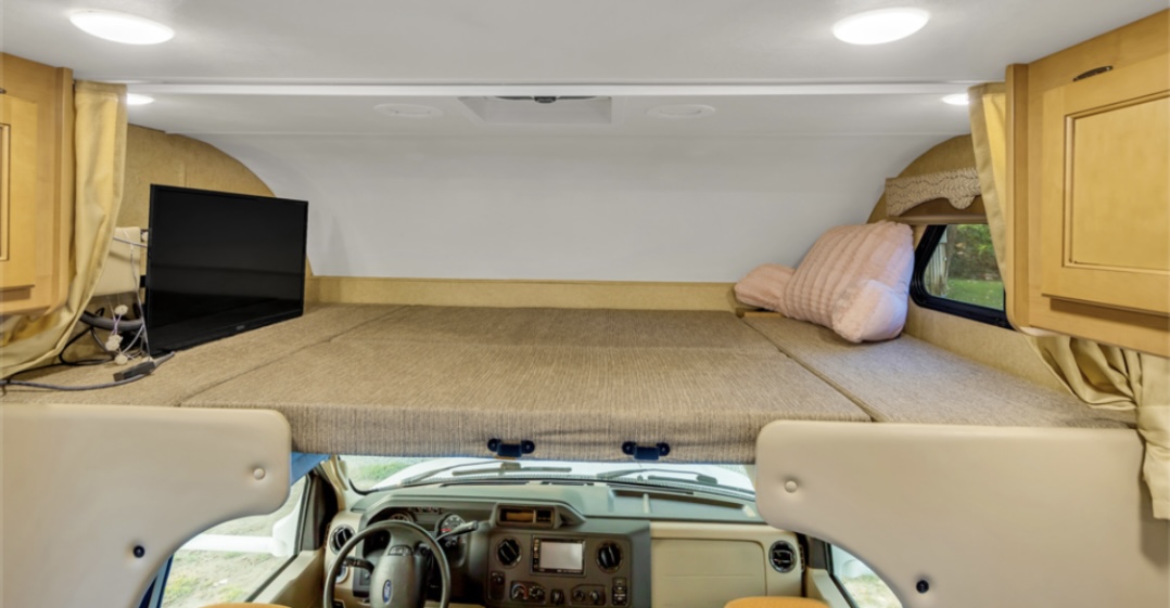 Inside this RV rental, a spacious cab-over bunk bed with a TV and storage offers a cozy sleeping area.. Thor Freedom Elite 2017