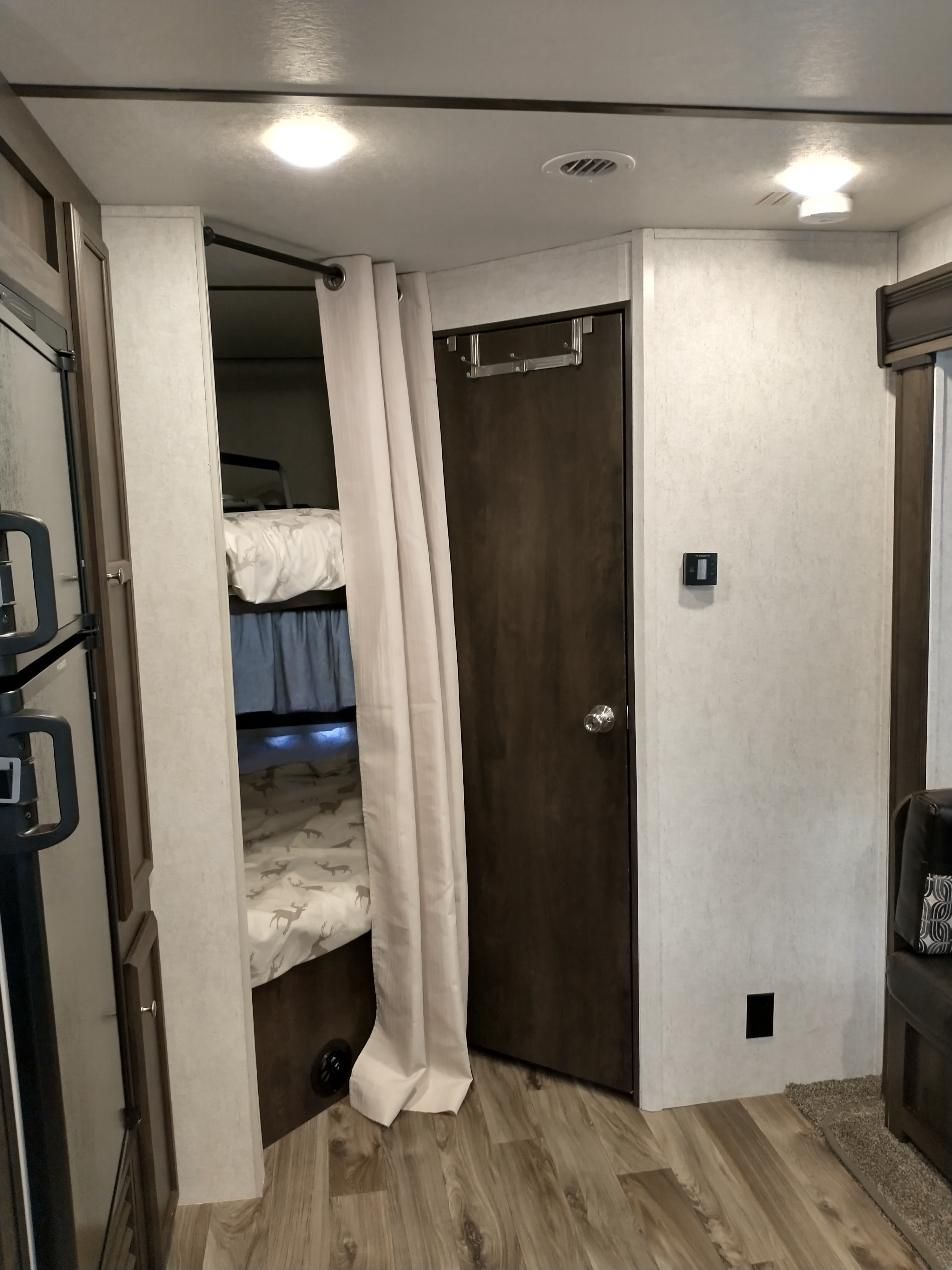 RV rental's interior features cozy bunk beds with privacy curtain, refrigerator, thermostat, and wood-look flooring.. Starcraft Autumn Ridge 2019
