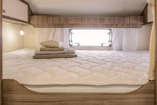 Cozy RV rental bedroom: quilted mattress, pillows, folded linens, window & lamp. Ready for your adventure.. Munro Munro Auto 2022
