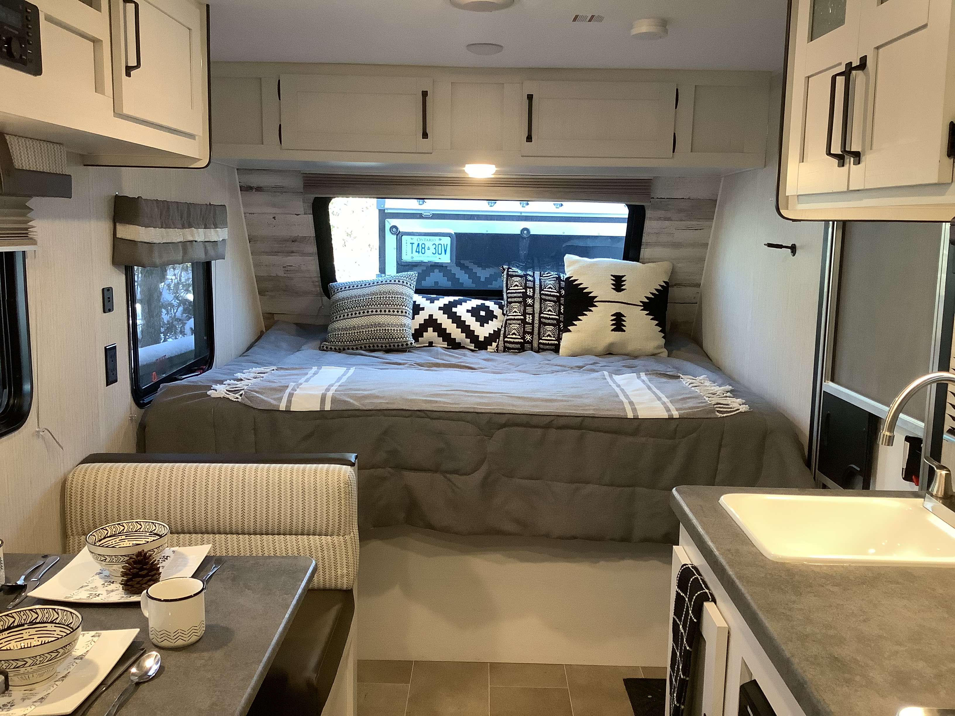 Ontario RV rental's cozy interior: bed, dining area, and kitchen with sink, ideal for your next trip.. Other Other 2021