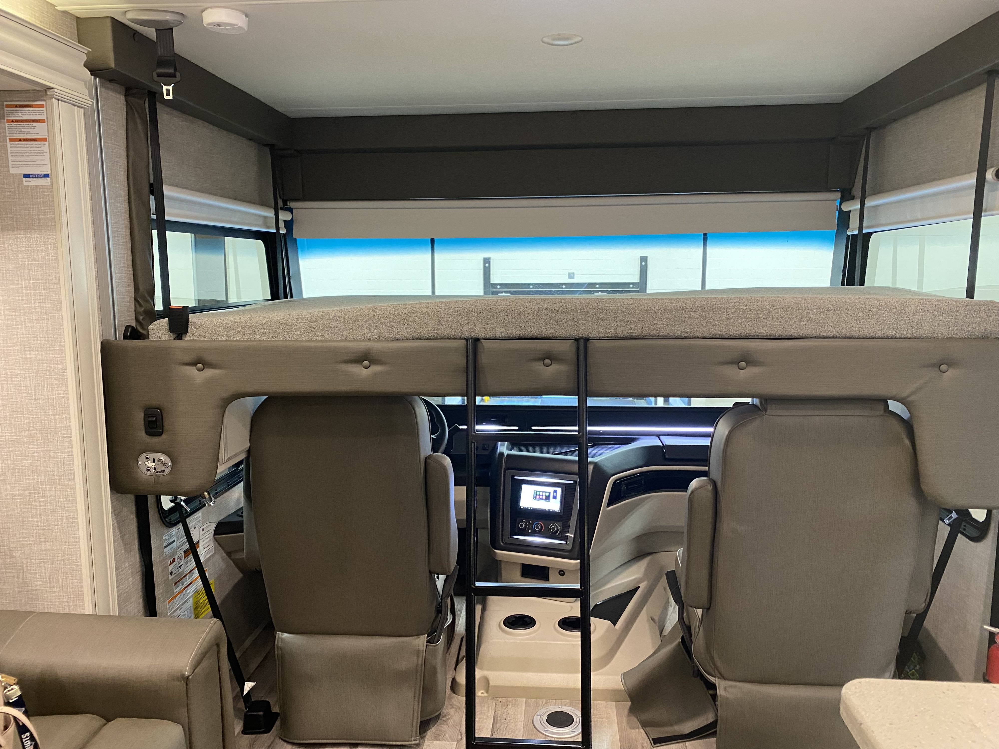 RV rental interior, showing the front cabin with driver/passenger seats, and an over-cab bunk bed with ladder.. Other Other 2022