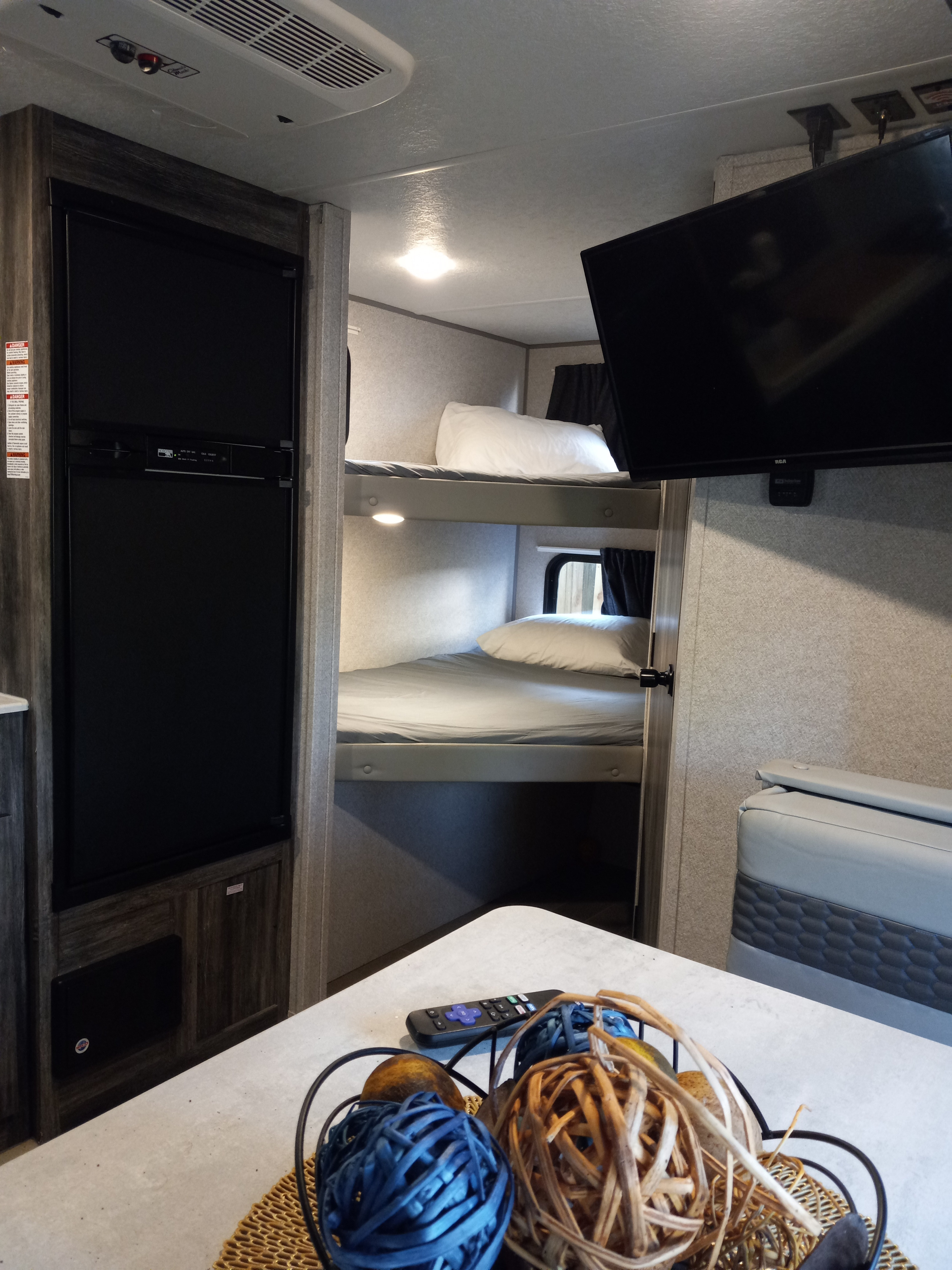 Cozy RV rental interior featuring bunk beds, a fridge, TV, and dining area. Perfect for family adventures!. Forest River Salem FSX PLATINUM 2020