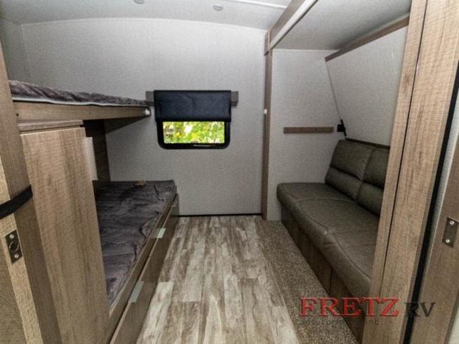 RV rental interior showing bunk beds on the left, a window, and a sofa on the right, providing versatile sleeping and seating.. Grand Design Imagine 2020