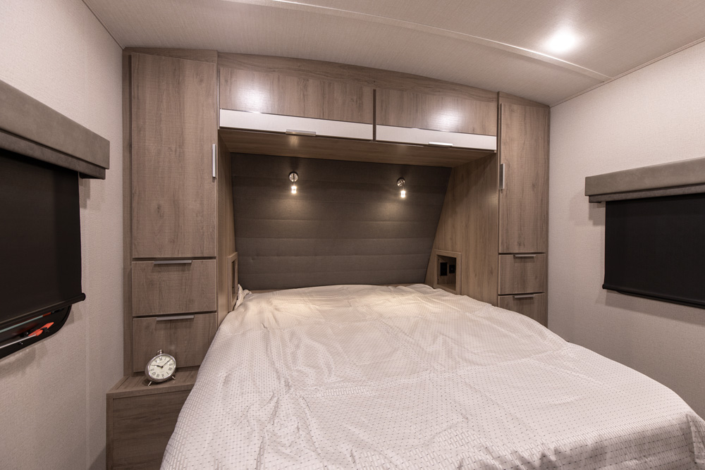Comfortable RV rental bedroom with modern built-in storage, soft lighting, and window blinds for privacy. Ideal for your next adventure.. Grand Design Imagine 2020