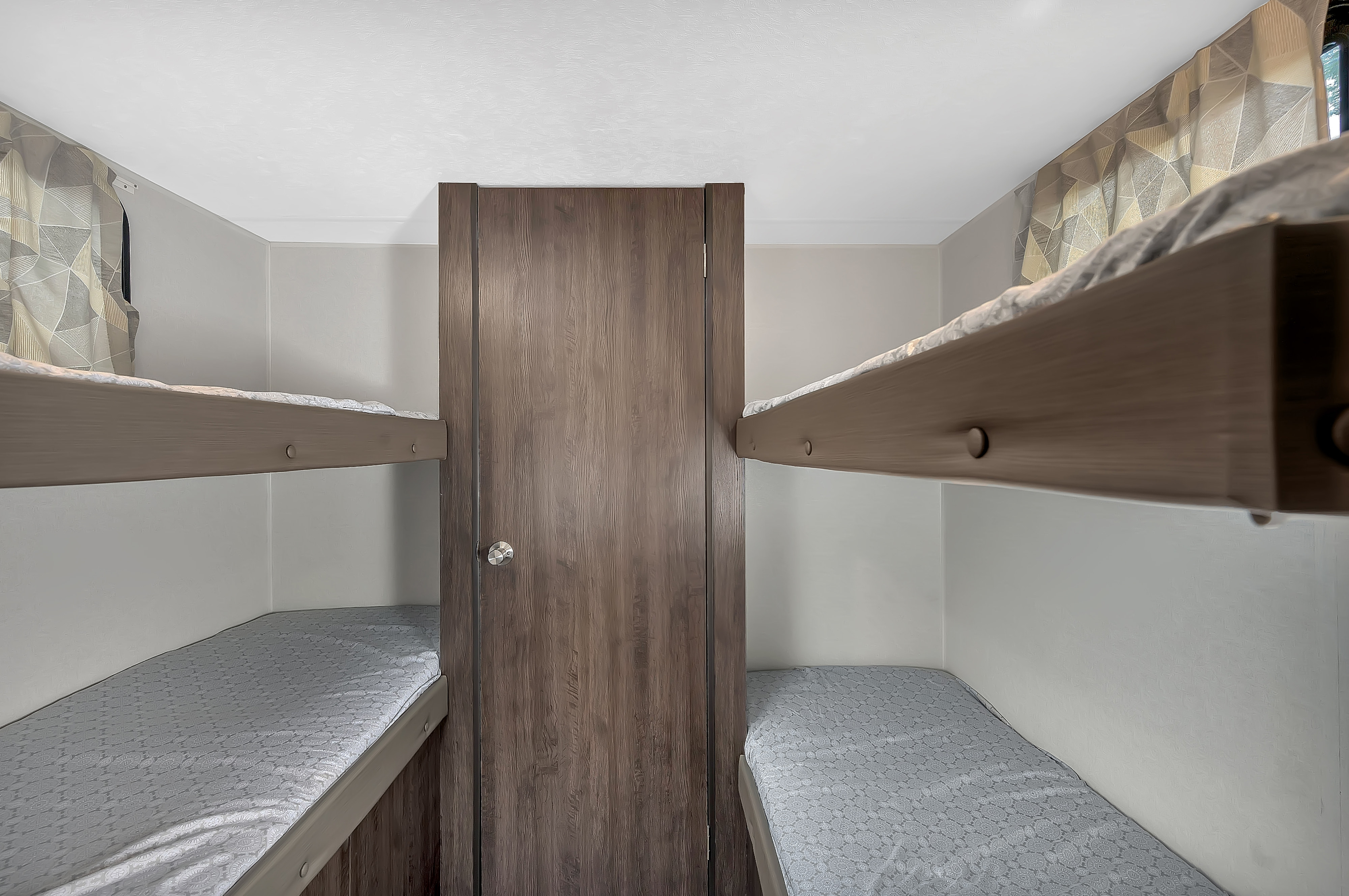 Compact RV rental sleeping area featuring bunk beds on both sides and a central wooden door.. Forest River Other 2020