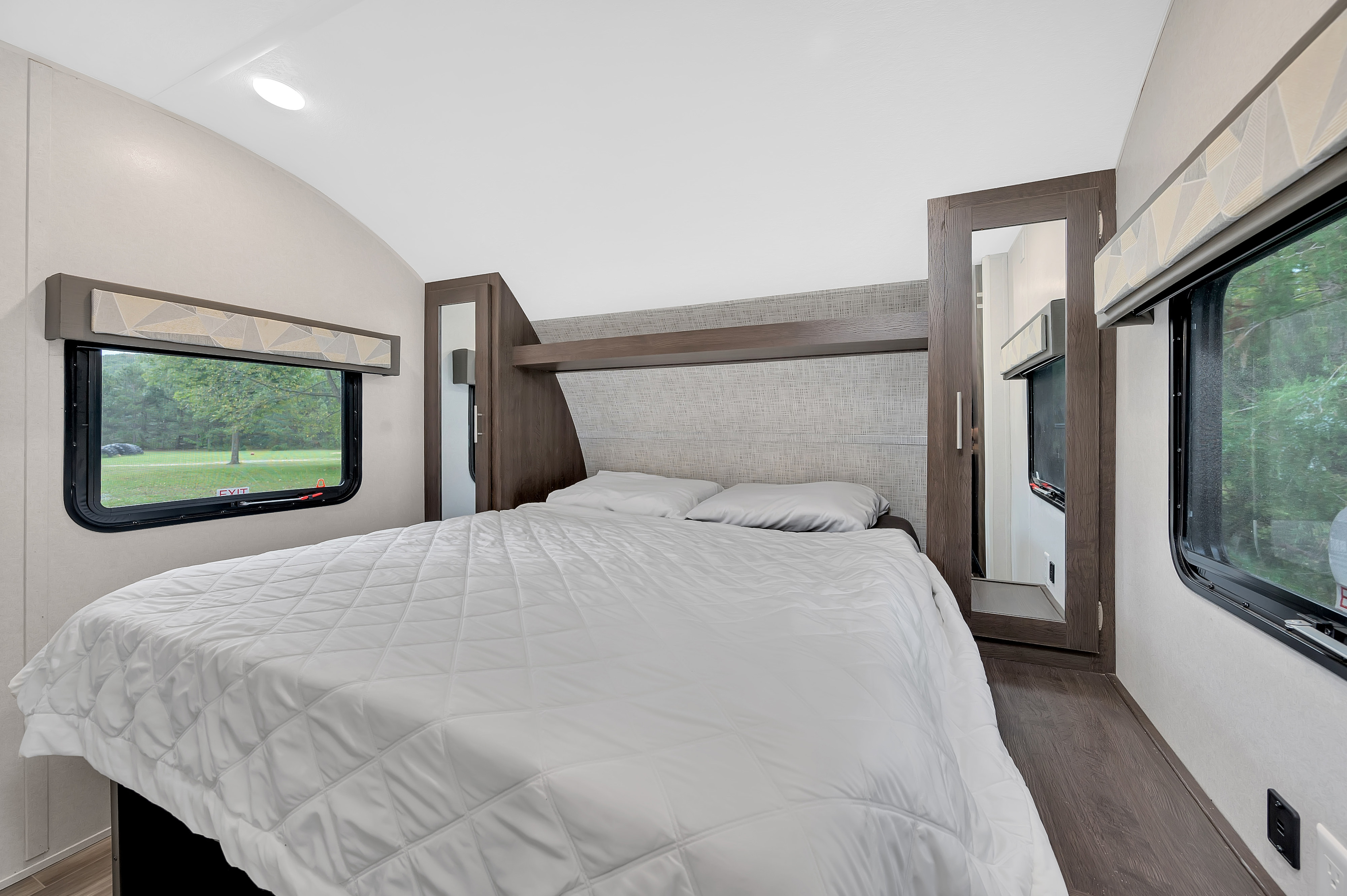 Step inside this modern RV rental bedroom featuring a cozy bed, ample light from windows, and smart storage solutions.. Forest River Other 2020