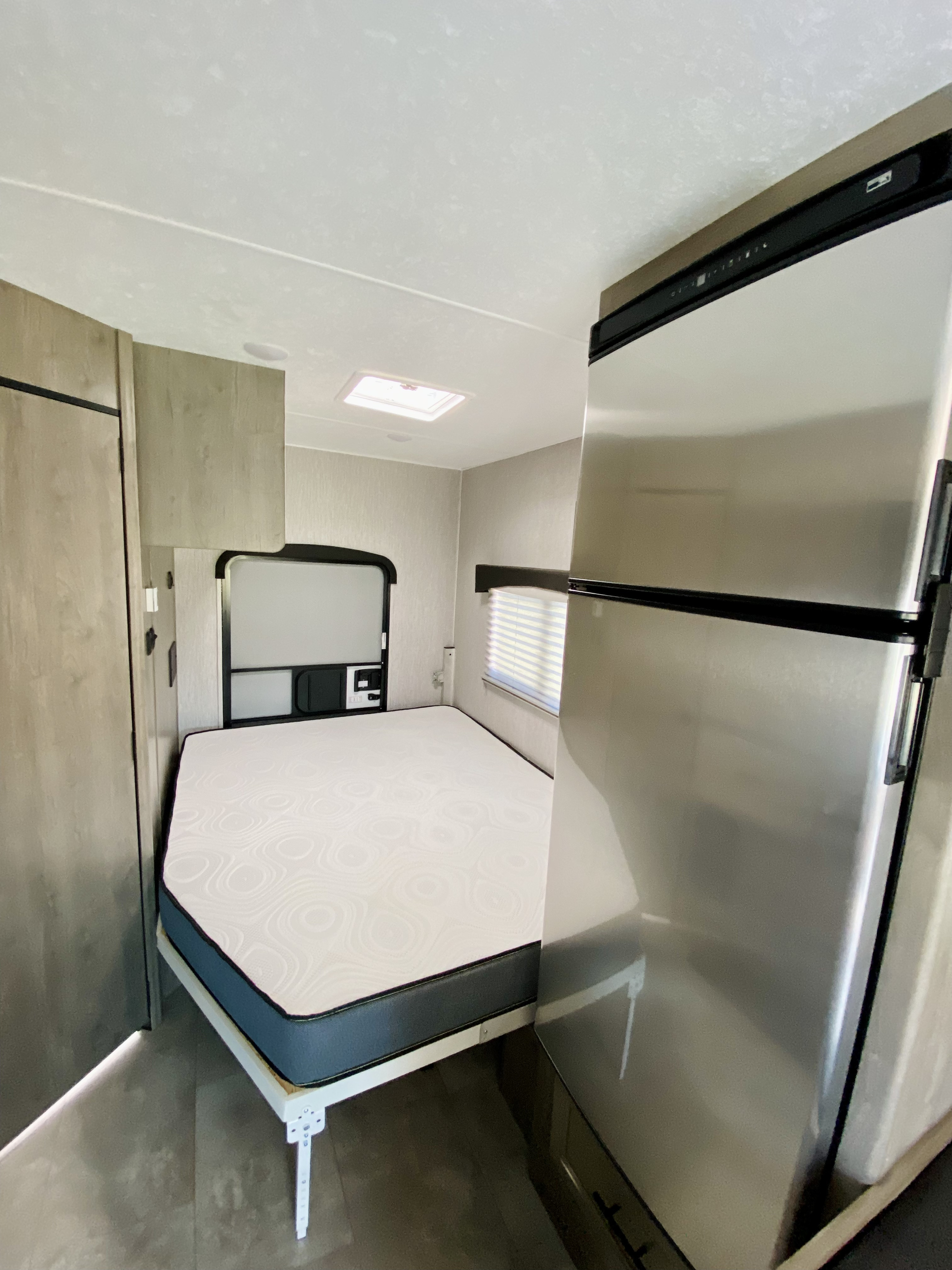 Bright RV rental interior: Features a comfortable bed, large fridge, and a skylight for natural light.. Coachmen Freelander 2021