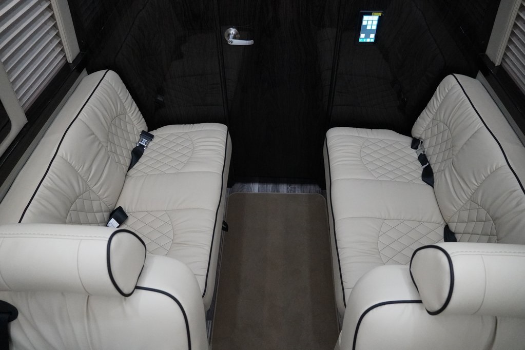 Luxury RV rental interior with opposing plush cream leather seats, quilted design, and dark wood accents.. Ultimate Toys Coach- Midwest Automotive Daycruiser D6 2022