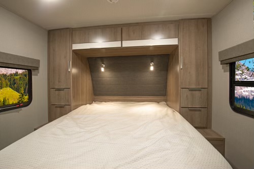 Comfortable RV rental bedroom with built-in storage, reading lights, and scenic window views for your next adventure.. Grand Design Imagine XLS 2020