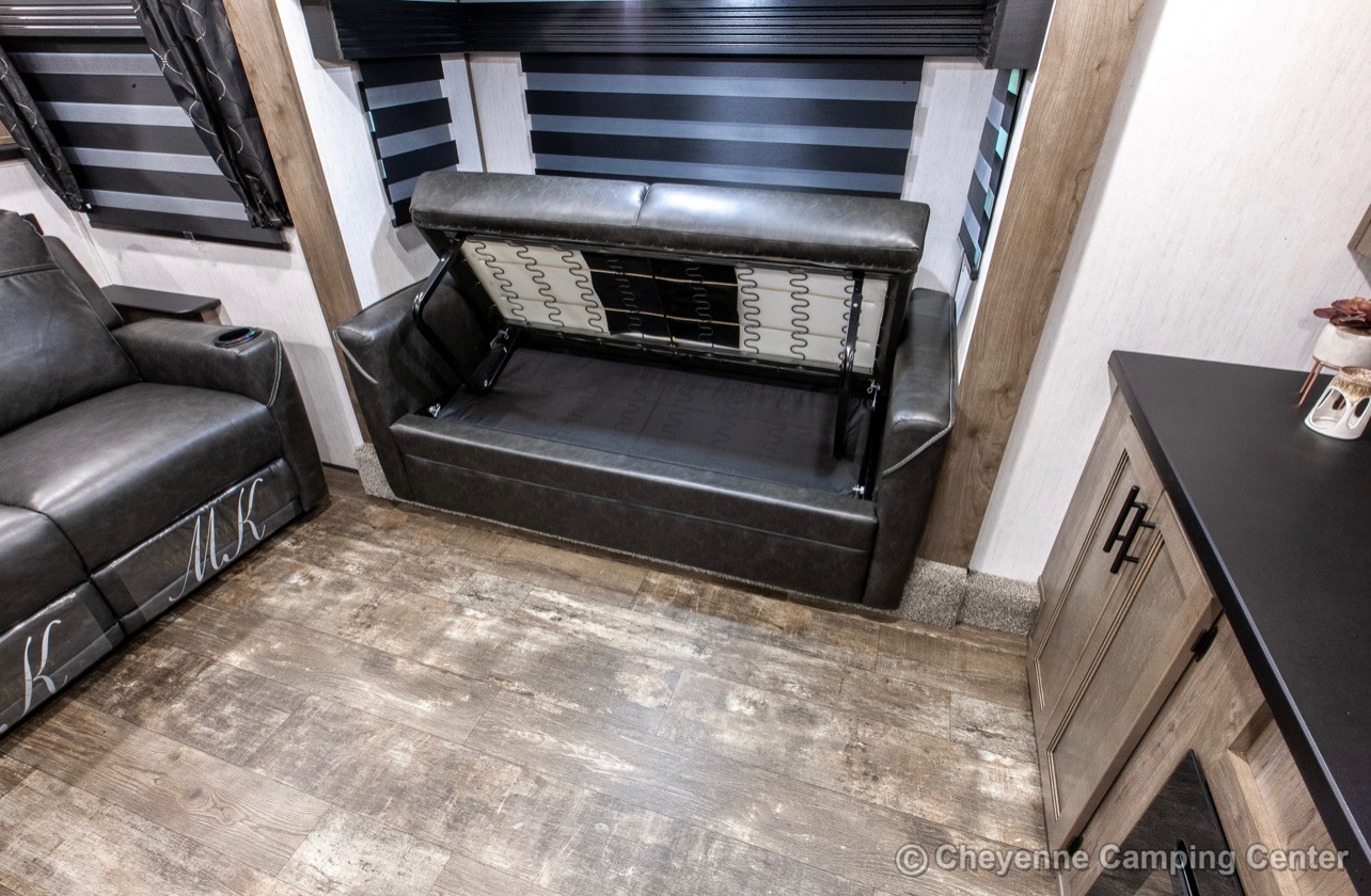 RV rental comfort: A dark leather sofa bed is open, revealing its frame, next to a matching reclining sofa.. Forest River Sabre 2021