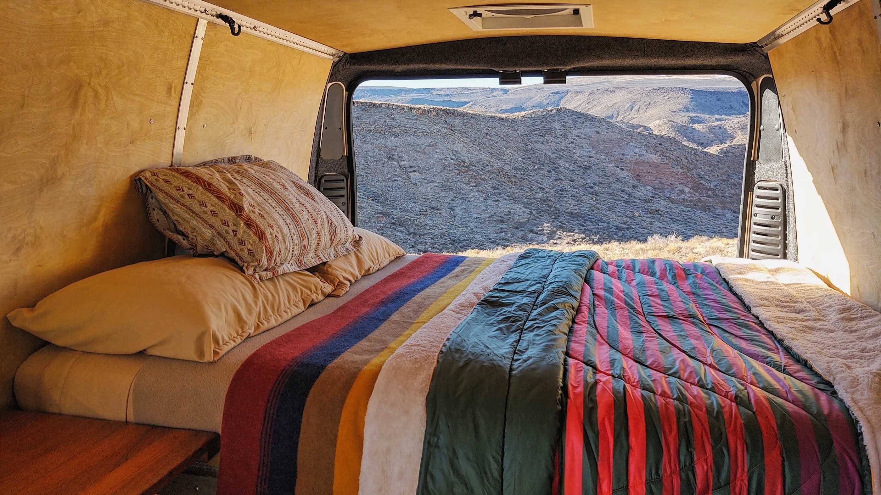 Cozy RV rental bed looking out to vast mountains. Enjoy nature from your comfortable camper van conversion.. Dodge ProMaster 2500 2020