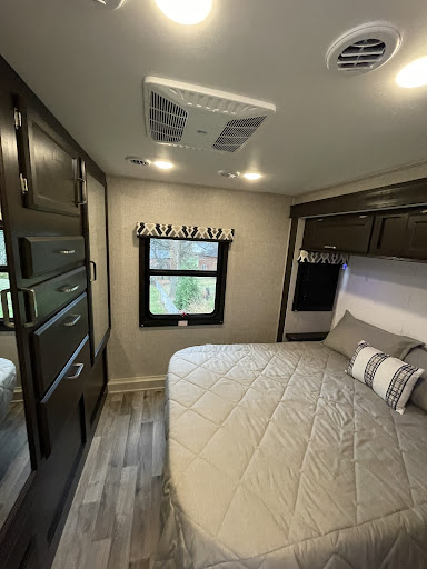 Comfortable RV rental bedroom with a cozy bed, ample storage, and window view for relaxing travels.. Entegra Coach Odyssey 2022