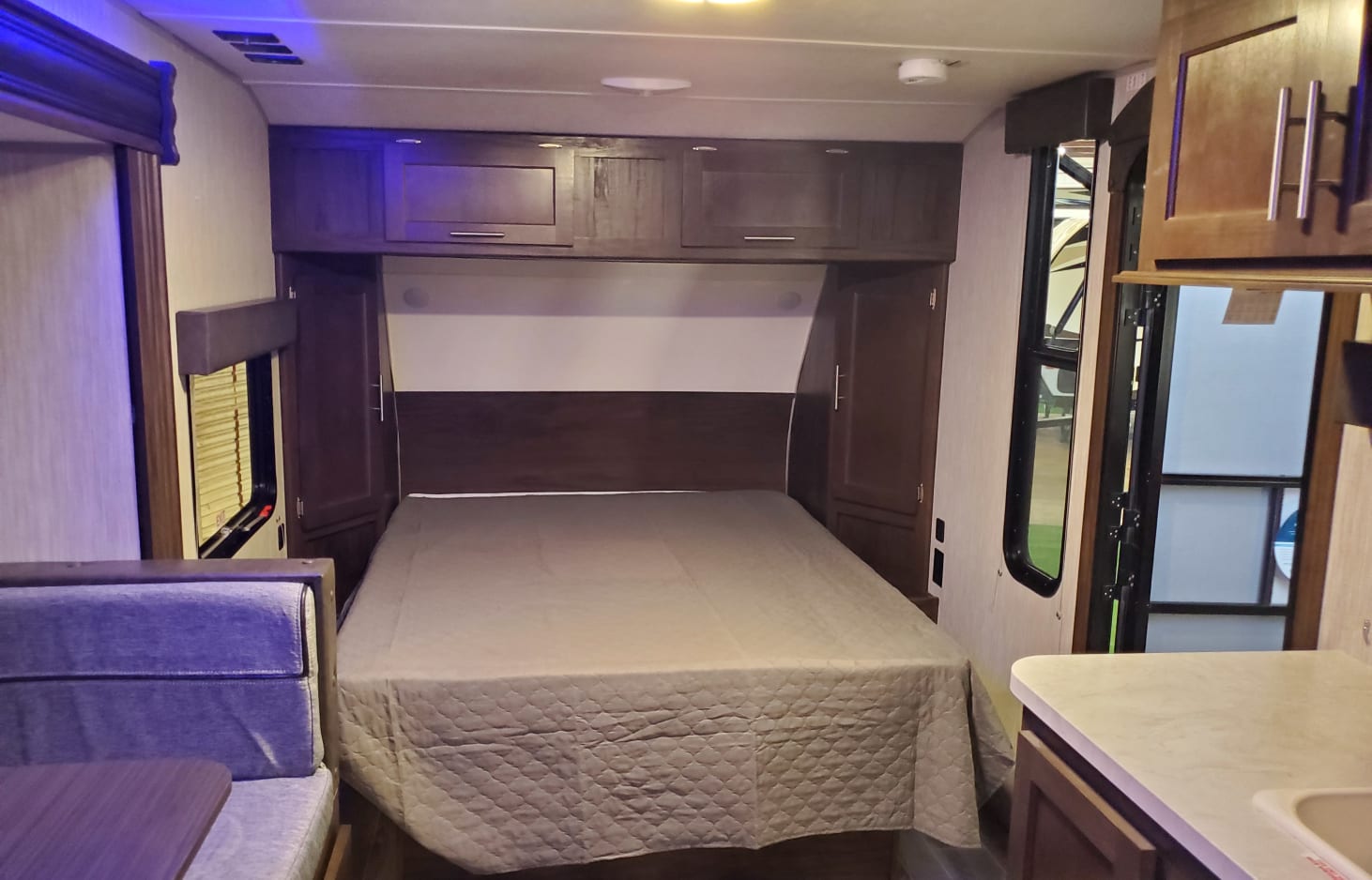 Inside an RV rental: a compact bedroom with bed, overhead cabinets, and a side dinette. Perfect for road trips.. Forest River Cherokee Wolf Pup 2020