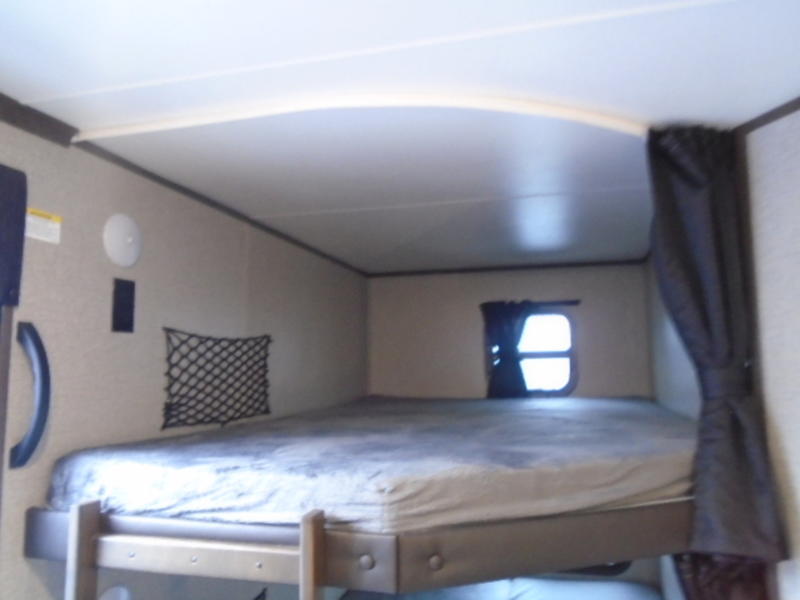 Cozy RV rental upper bunk bed area with window, mesh storage net, and dark privacy curtain.. Jayco Jay Flight 2020