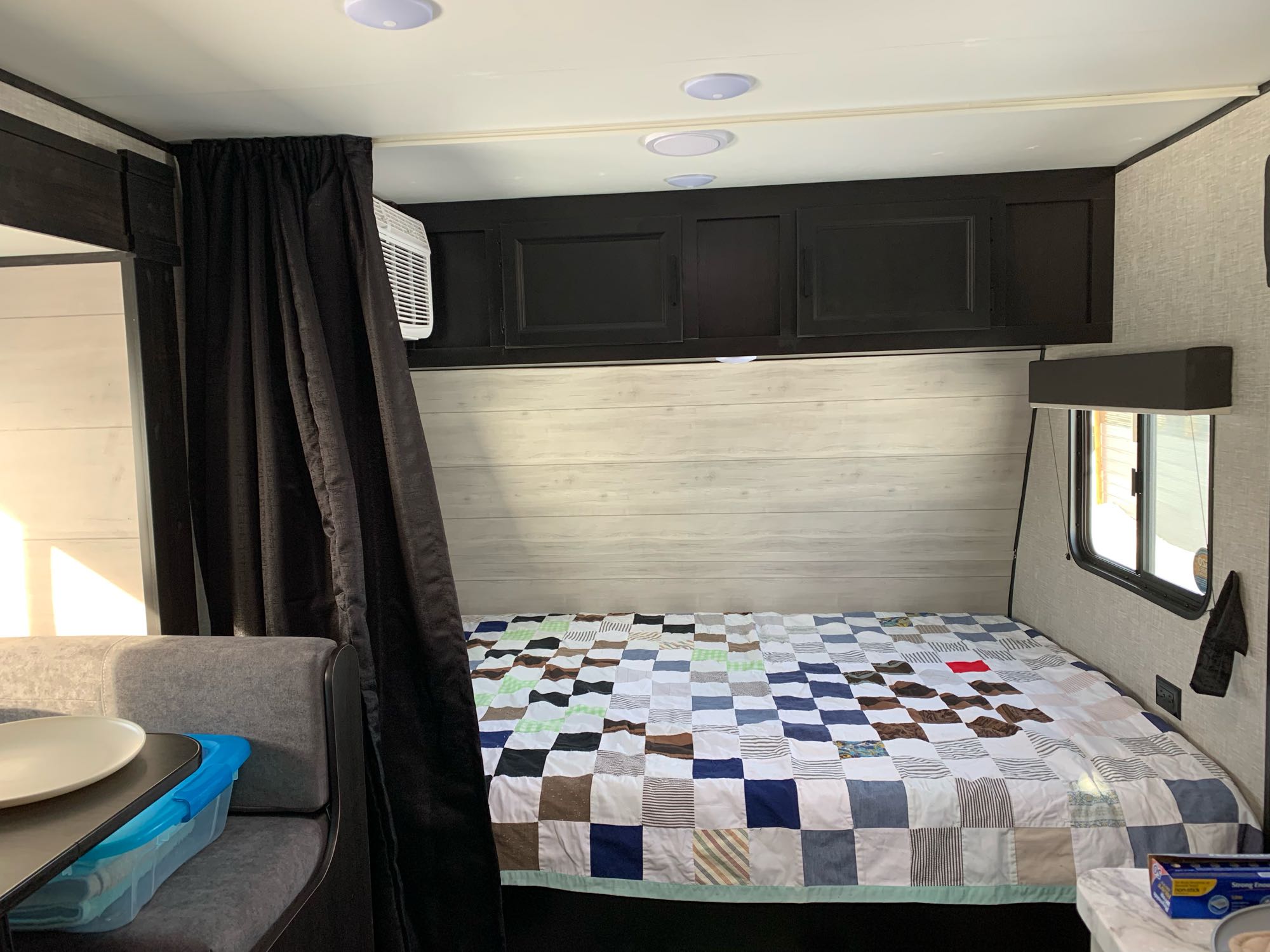 RV rental interior: Cozy sleeping area with a colorful patchwork quilt, dark cabinets, AC unit, and seating.. Jayco Jay Flight 2022