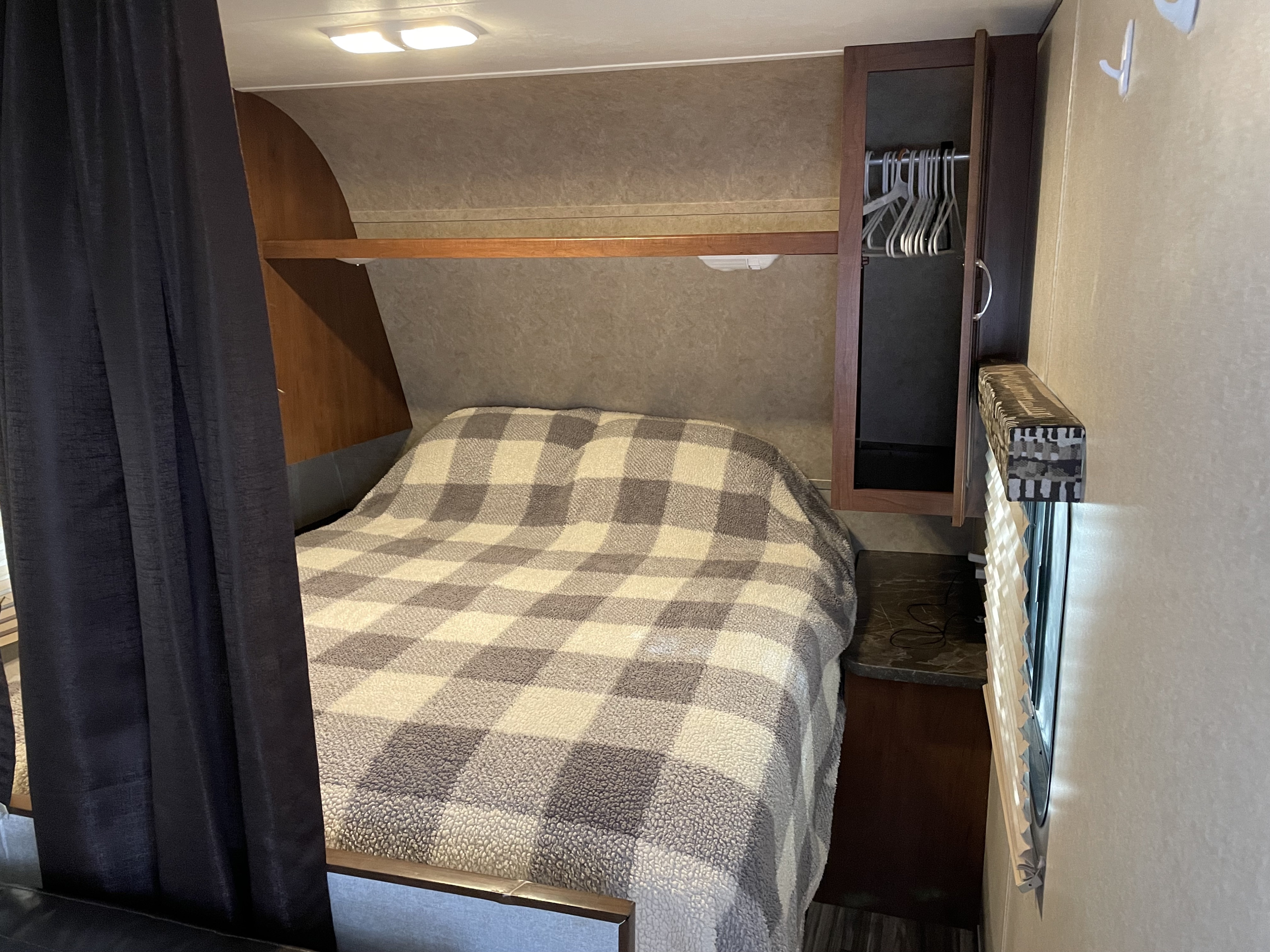 Inside an RV rental: a cozy bedroom features a plaid bed, overhead storage, and a small closet with hangers.. Jayco Jay Flight SLX 2017