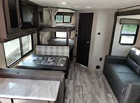 Spacious RV rental interior: A modern mobile home with dinette, bunk beds, sofa, and kitchen counter for family trips.. Grand Design Transcend Xplor 2022
