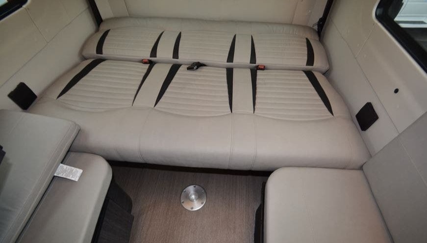 RV rental interior featuring light-colored, versatile seating with black accents and seatbelts, likely converting to a bed.. Winnebago Era 2021