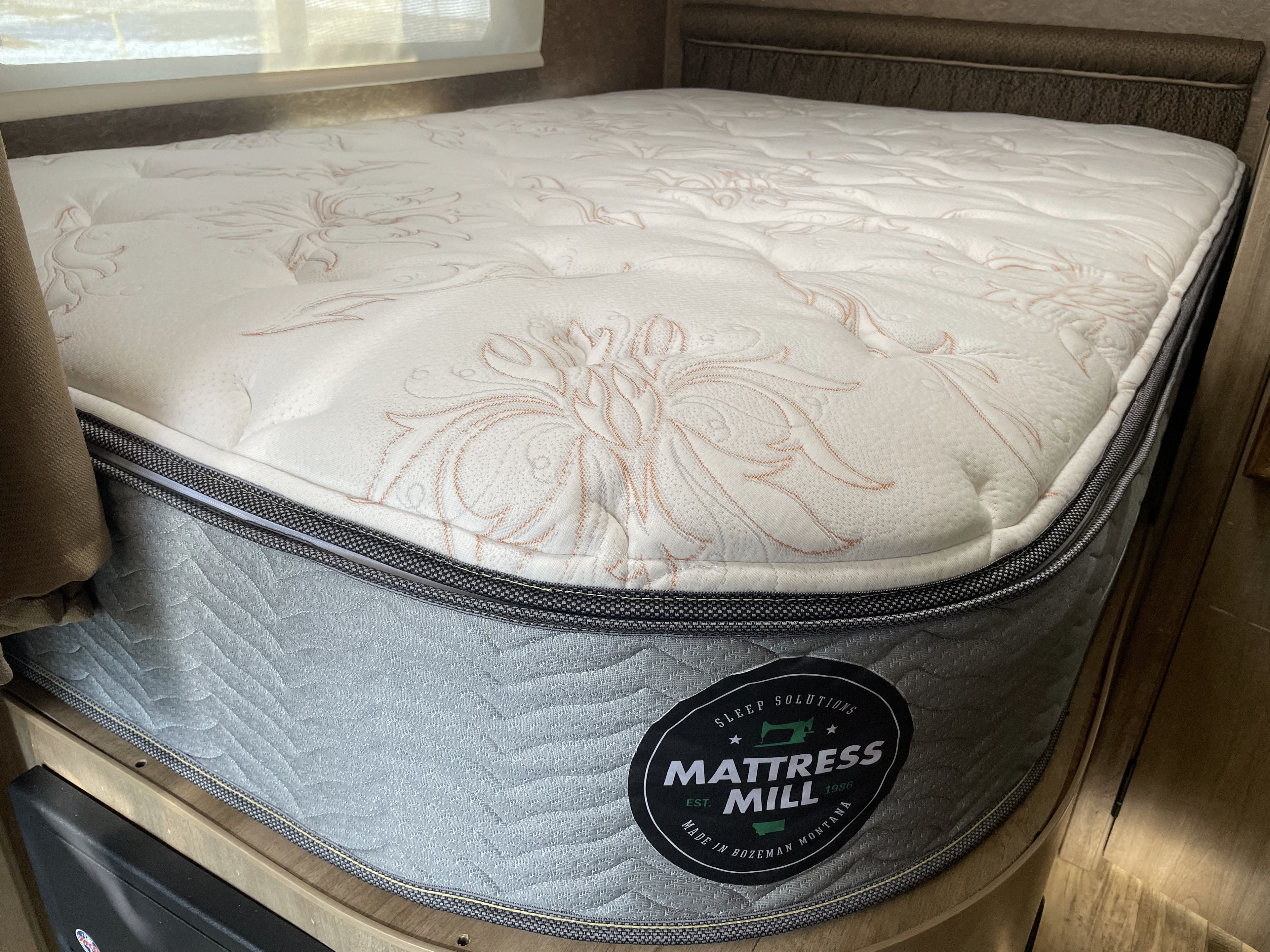 Comfortable Mattress Mill bed in an RV rental, featuring a quilted top and a label from Bozeman, Montana.. Coachmen Prism 2015
