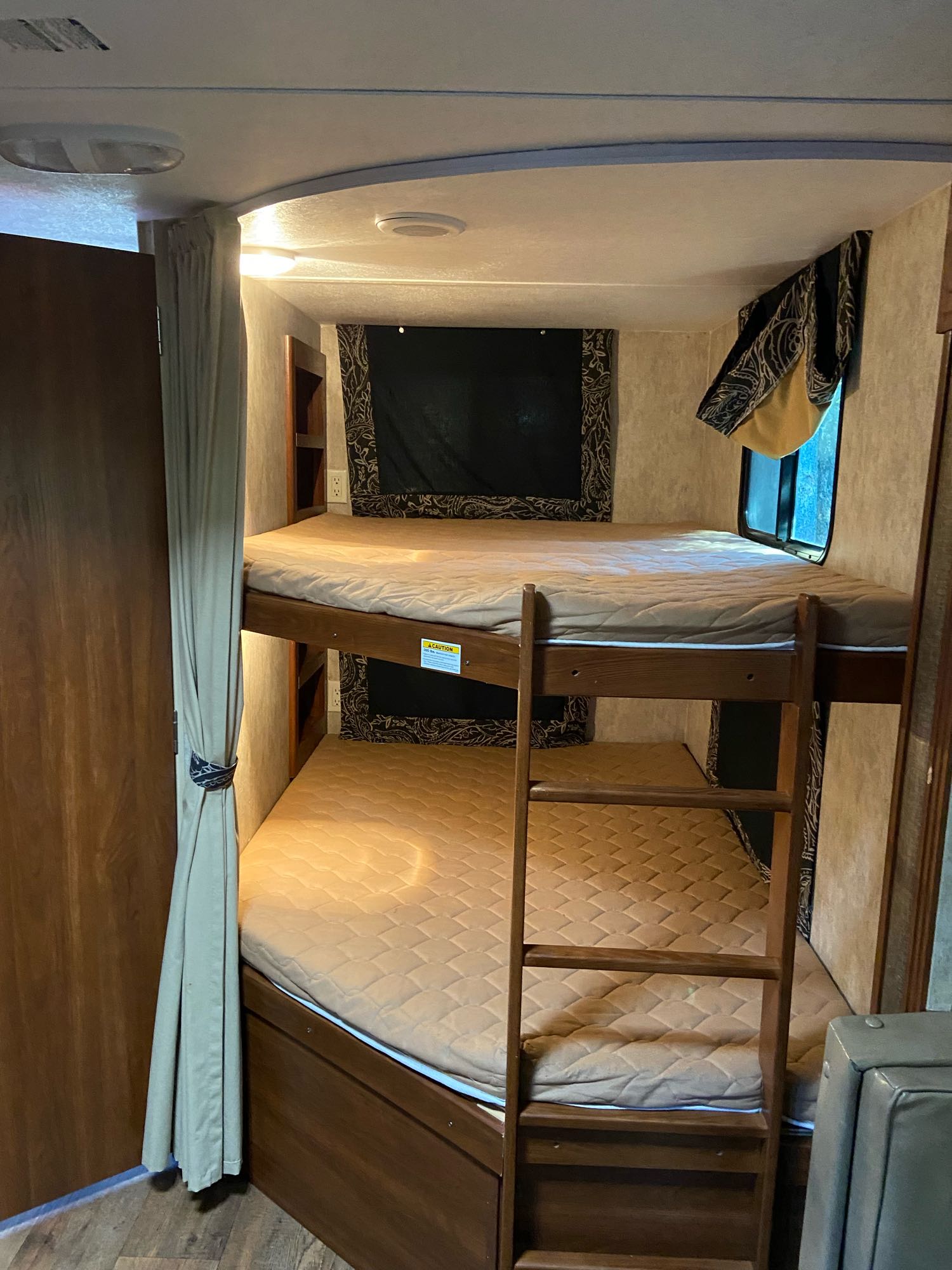 Cozy RV rental bunk beds with ladder and mattresses provide comfortable accommodation. Well-lit interior for family travel.. Keystone Bullet 2015