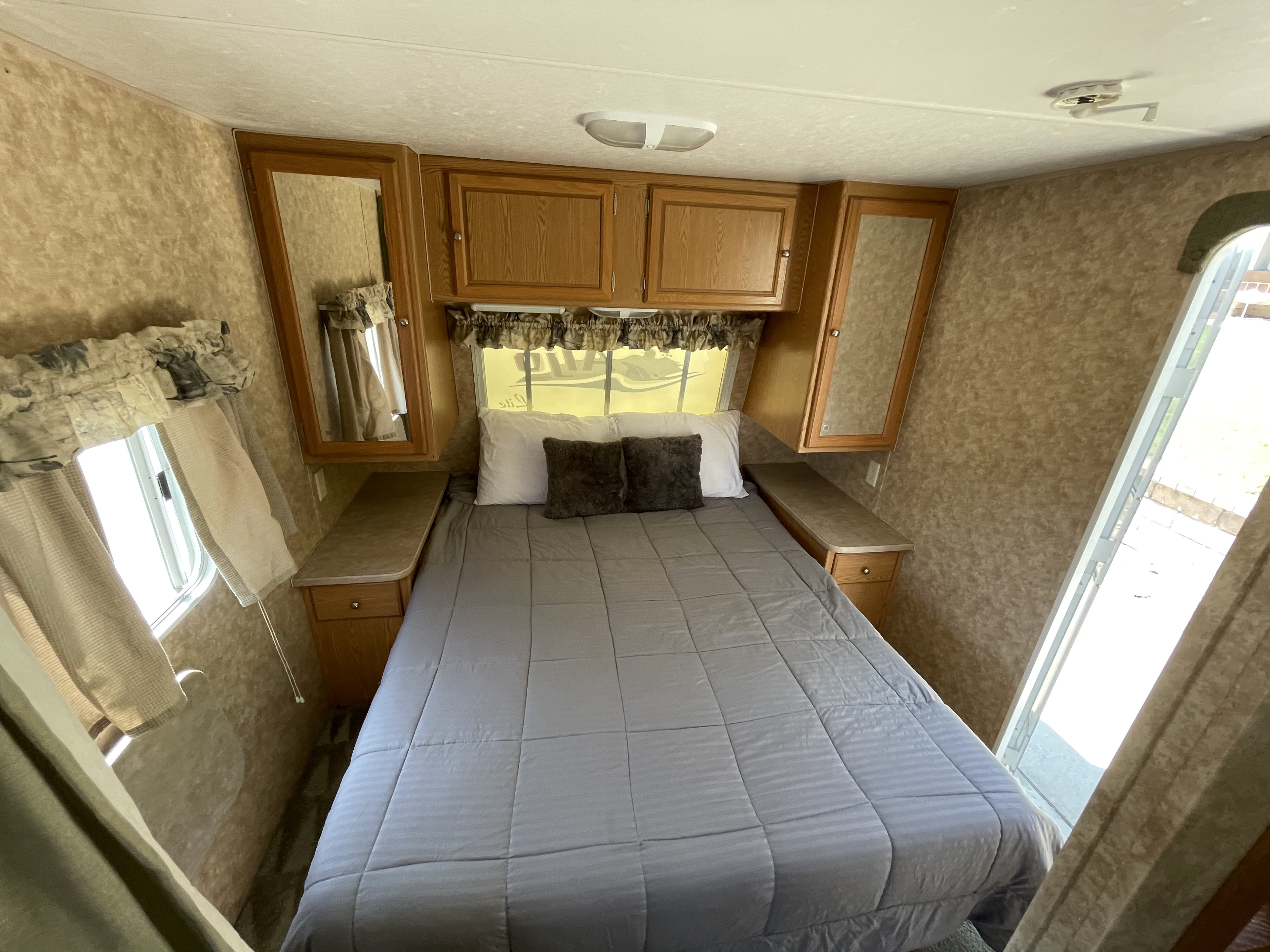 Cozy RV rental bedroom with a comfortable bed, overhead storage, and side windows. Perfect for travel adventures.. Skyline Aljo 2007