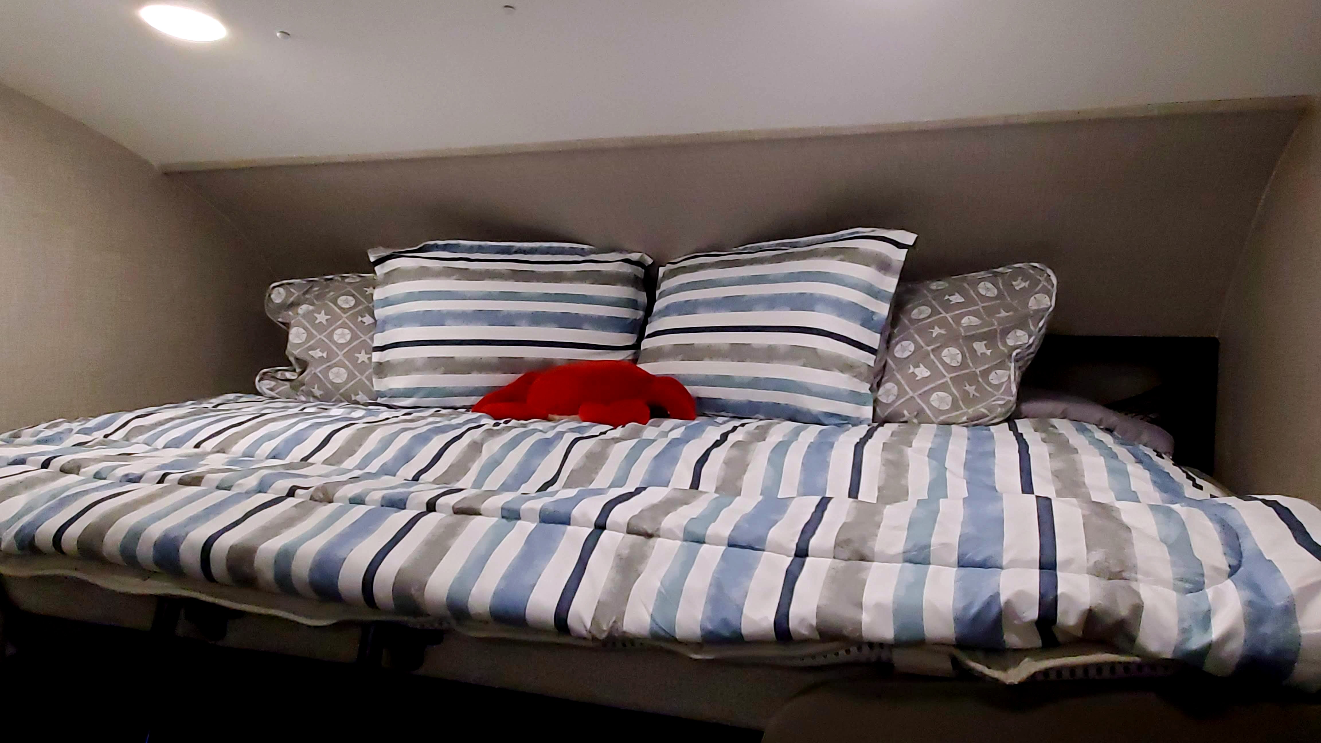 RV rental bunk bed: blue & gray striped bedding, nautical pillows, and a red lobster toy create a cozy sleep space.. Jayco Redhawk 2022