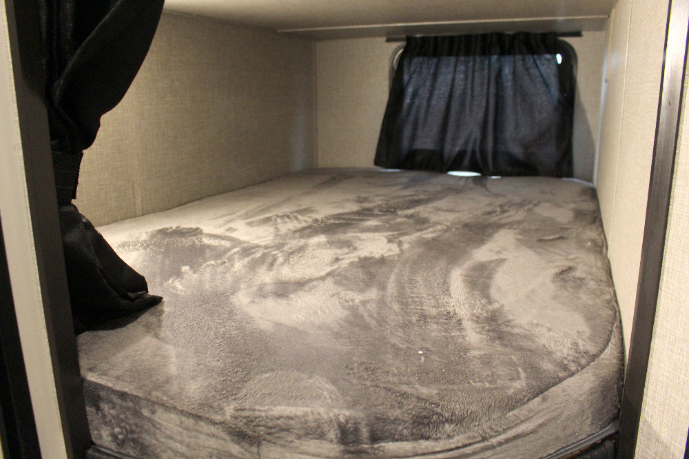 Cozy RV rental bunk bed with a grey mattress and dark privacy curtains, ready for your next adventure.. Jayco Jay Flight SLX 224BH 2022