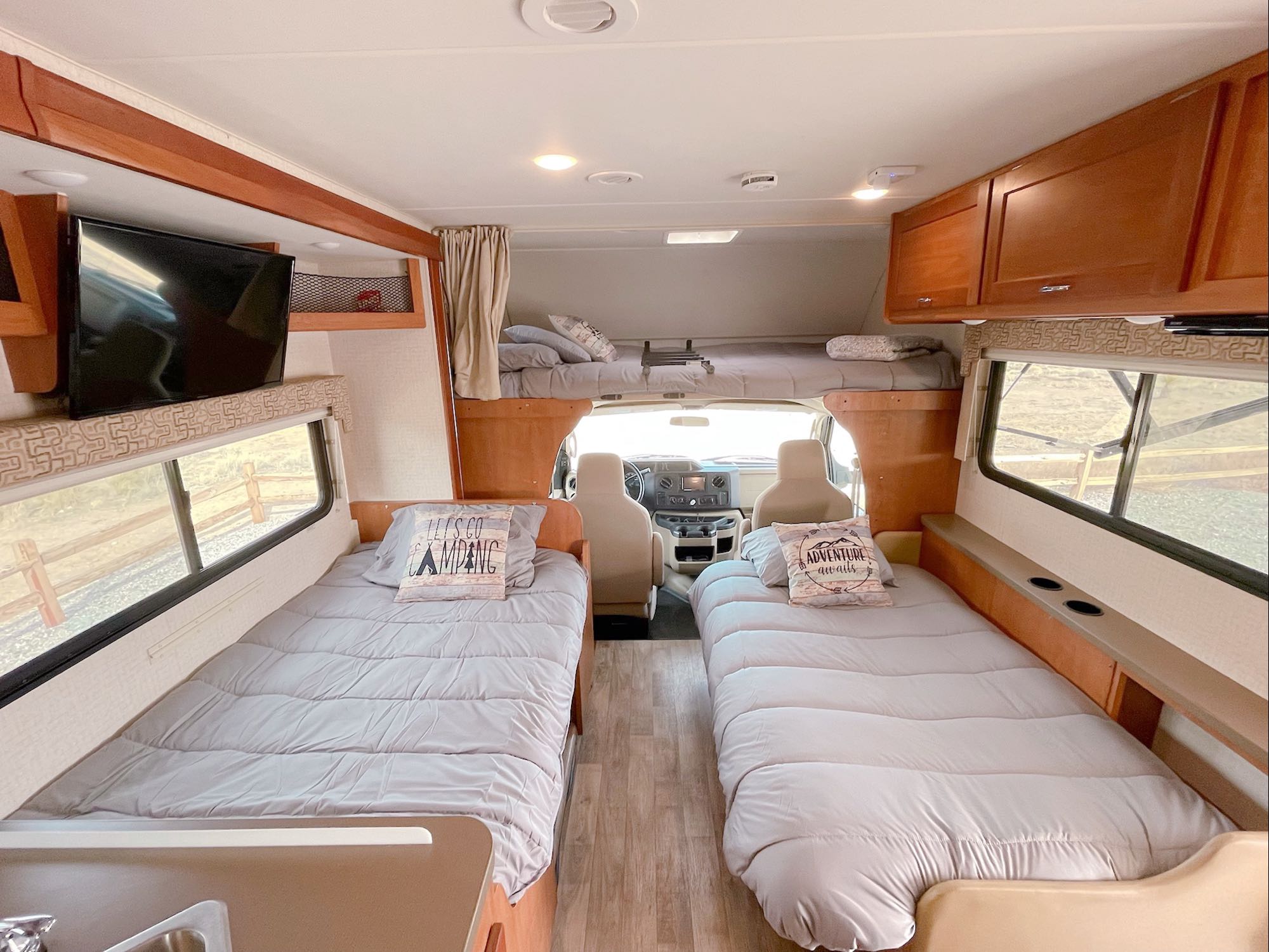 Cozy RV rental interior showing multiple beds (cab-over & twin), wood flooring, and TV, ready for adventure.. Winnebago Minnie Winnie 2017