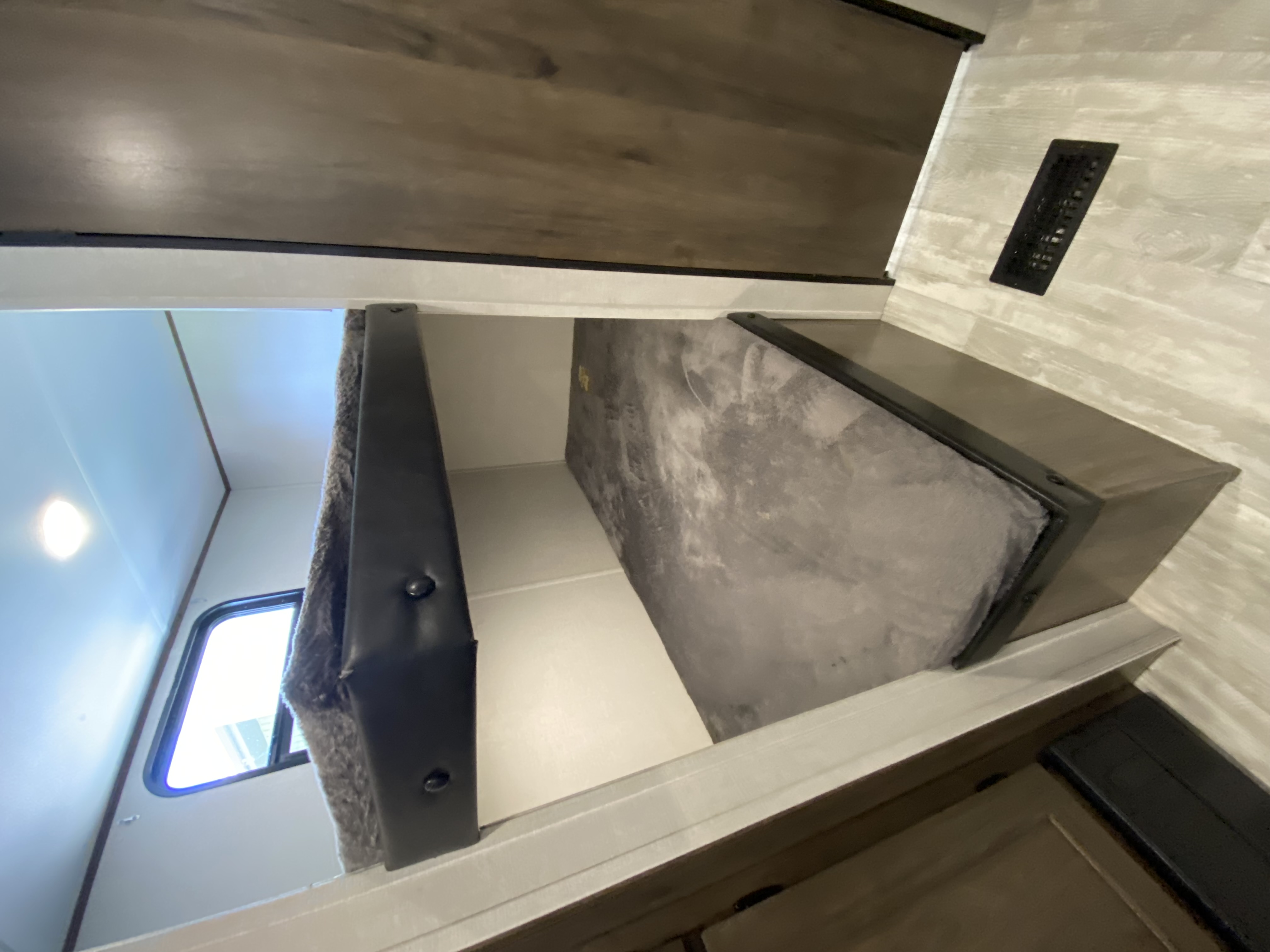 Cozy RV rental bunk beds. This mobile sleeping area features a lower grey mattress, window, and patterned walls for comfort.. Avenger LE 2021