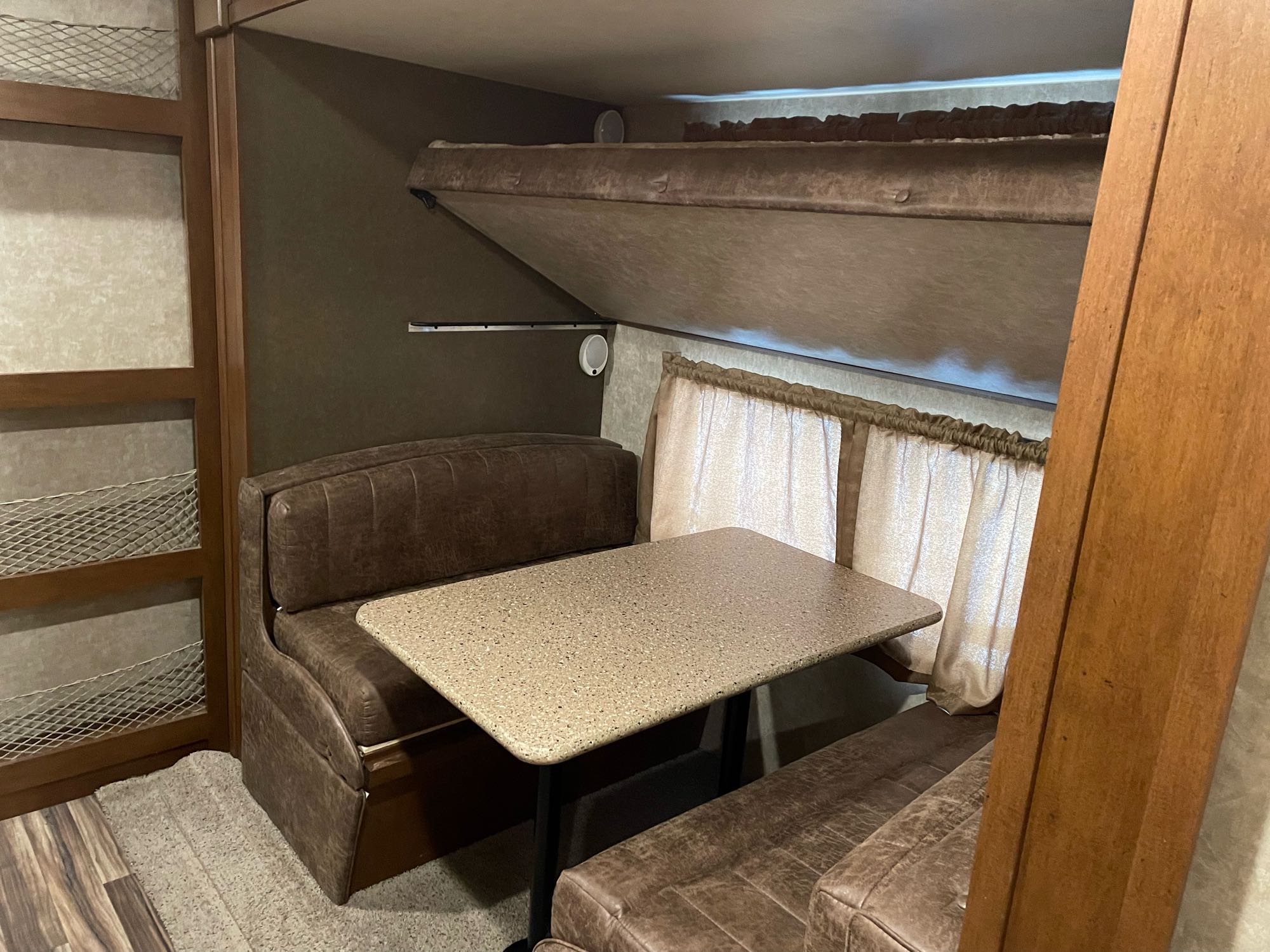 This RV rental interior features a cozy dinette with two benches and a table, plus an overhead bunk bed, perfect for travel.. Open Range Light 2017
